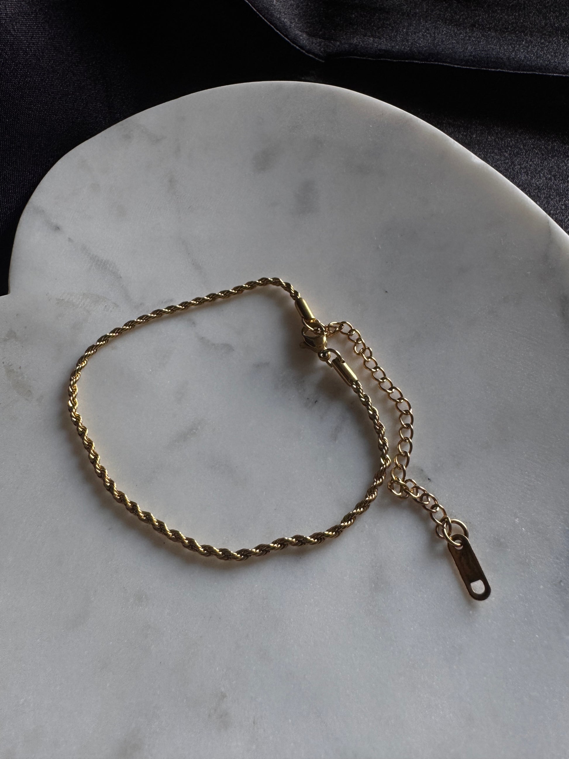 Gold rope anklet on a marble surface