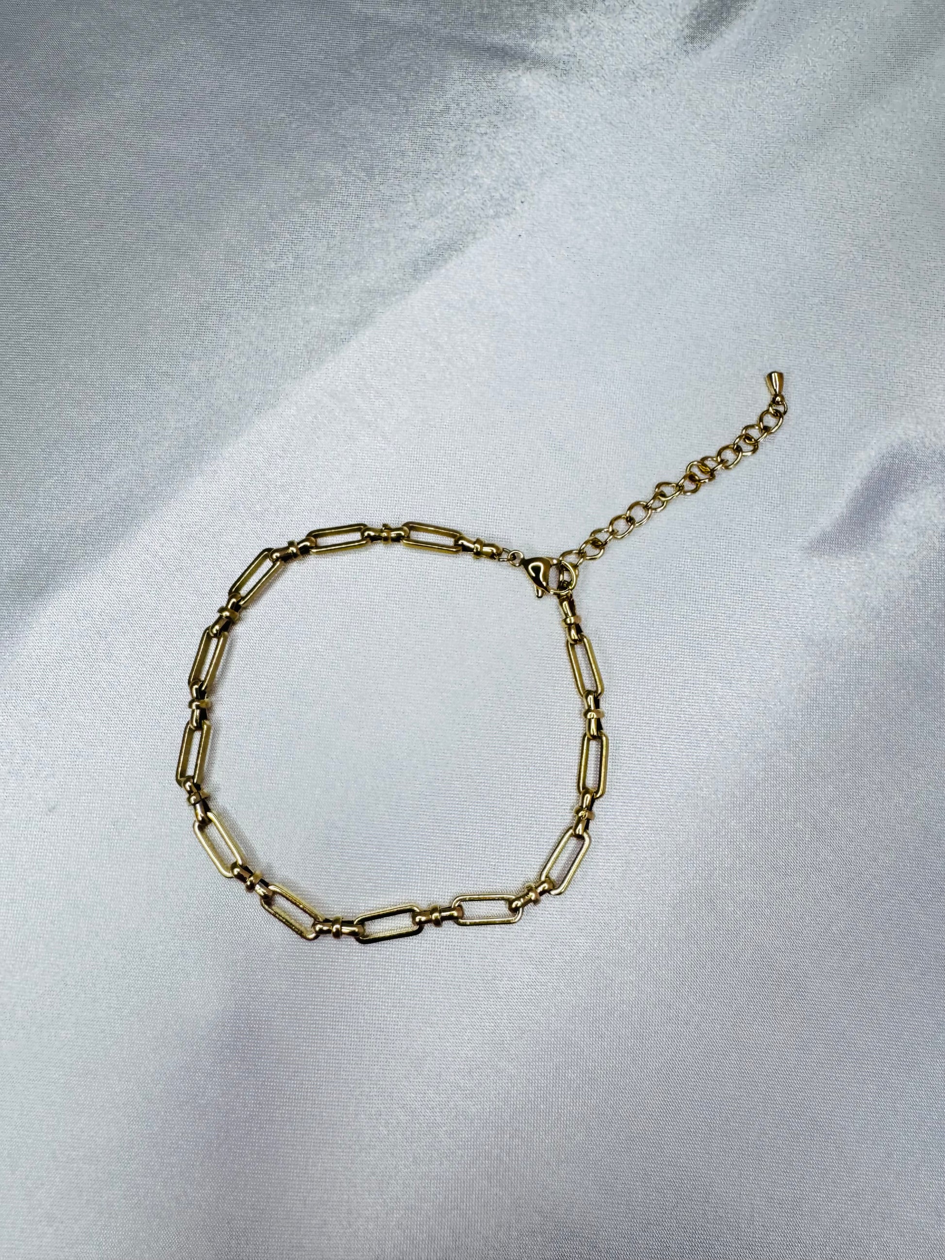 Gold bold link anklet on a light gray fabric background