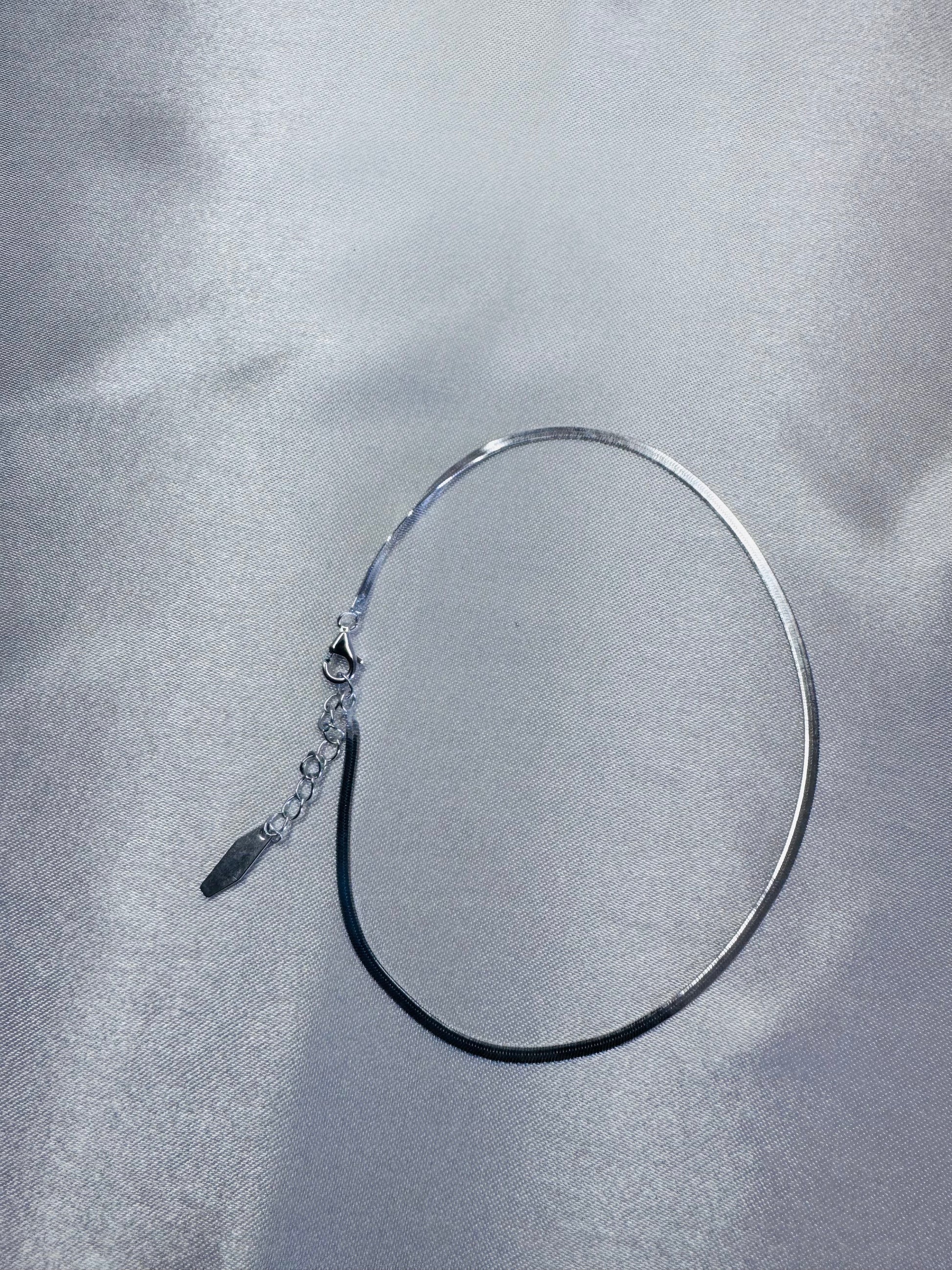 Silver anklet on a textured gray surface