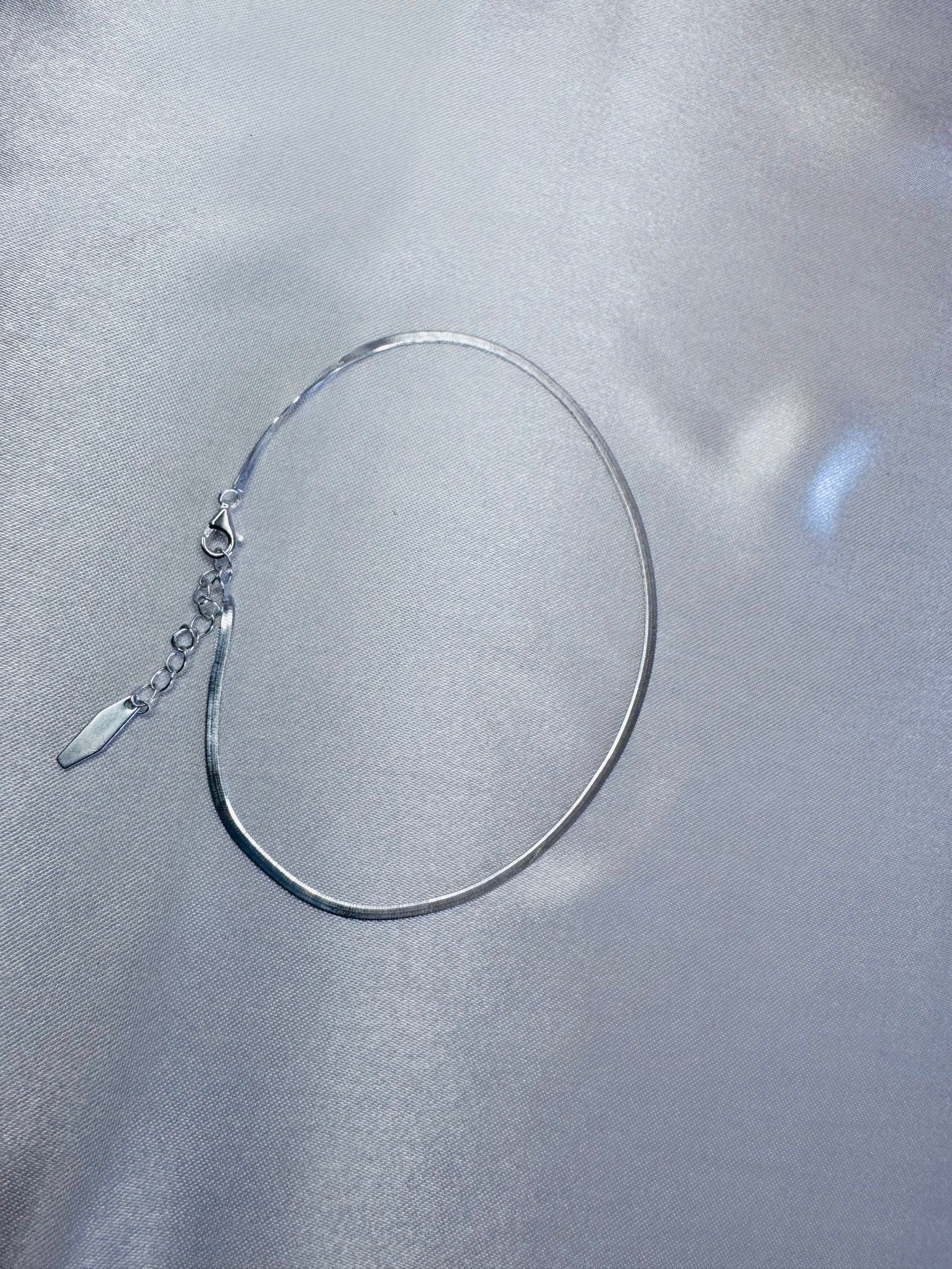 Silver anklet on a reflective silver surface