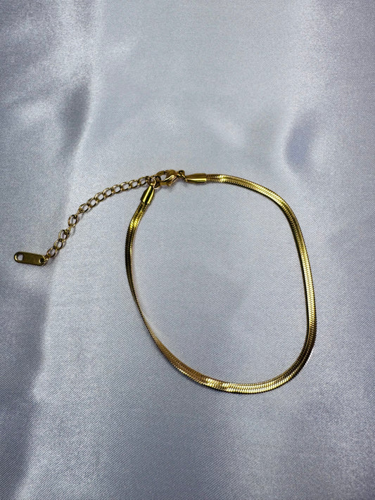 Gold bracelet on a light gray fabric background