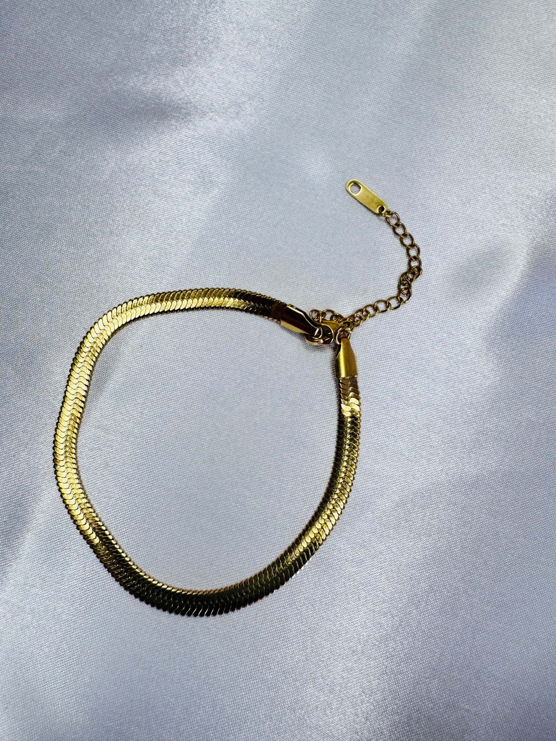 Gold bracelet on a light gray background