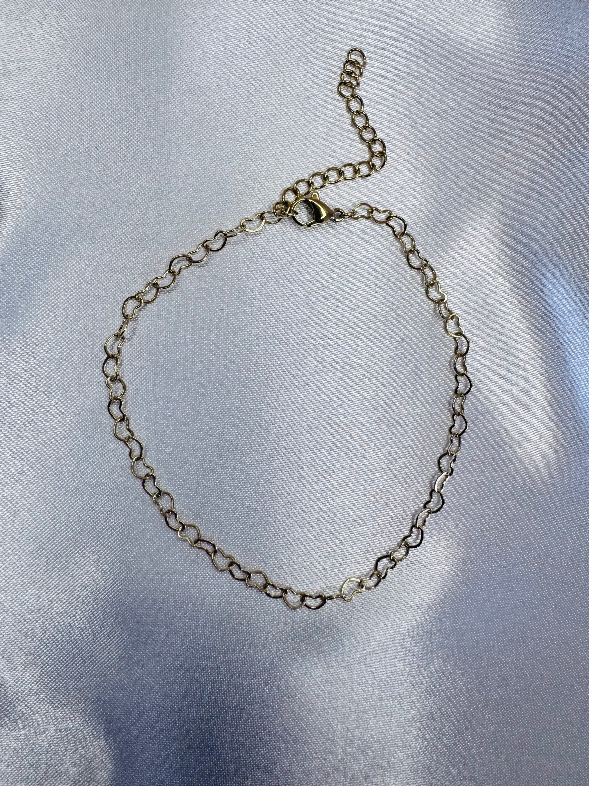 Silver chain bracelet on a reflective silver surface