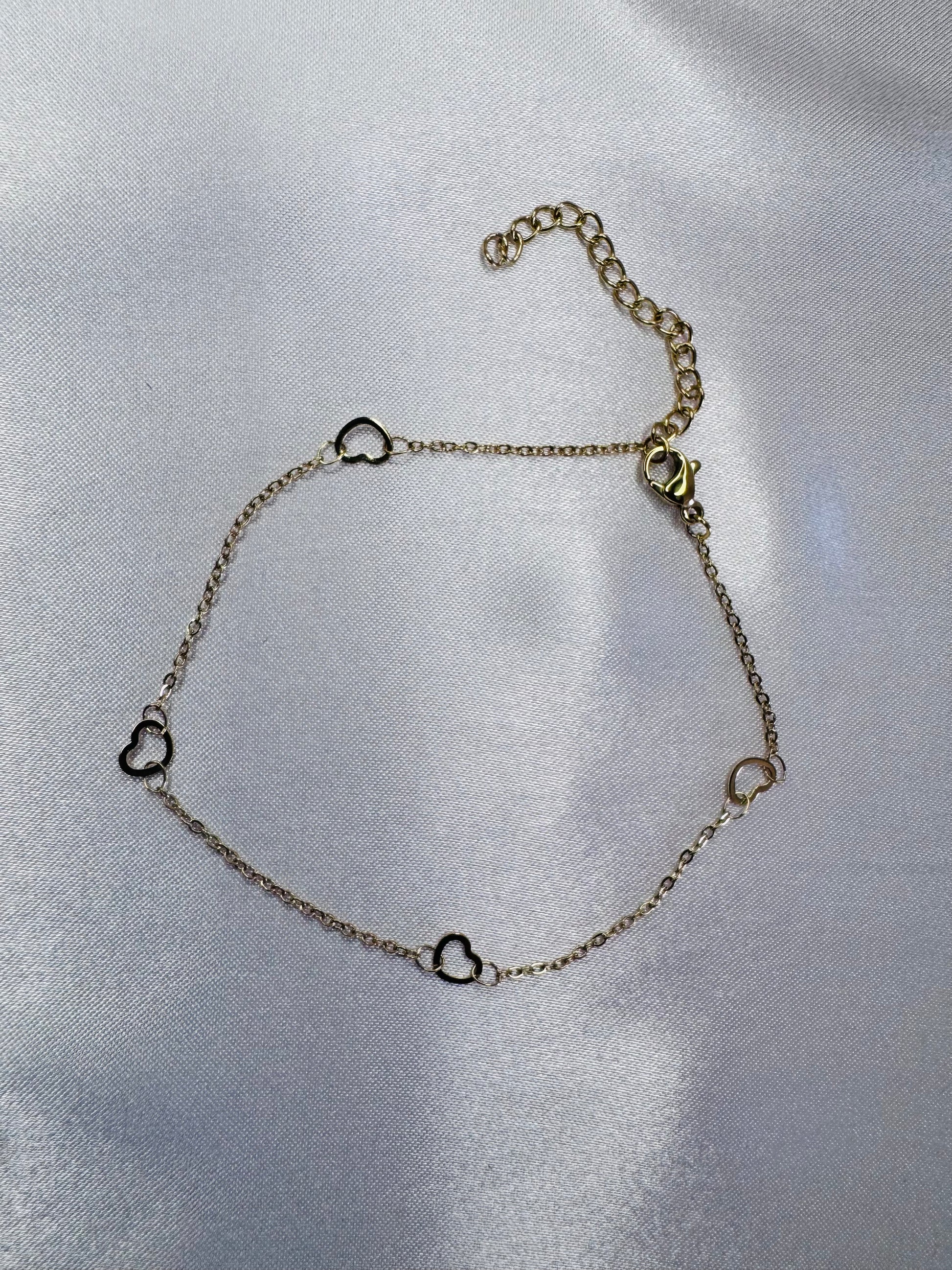 Silver anklet with heart-shaped charms on a silver background