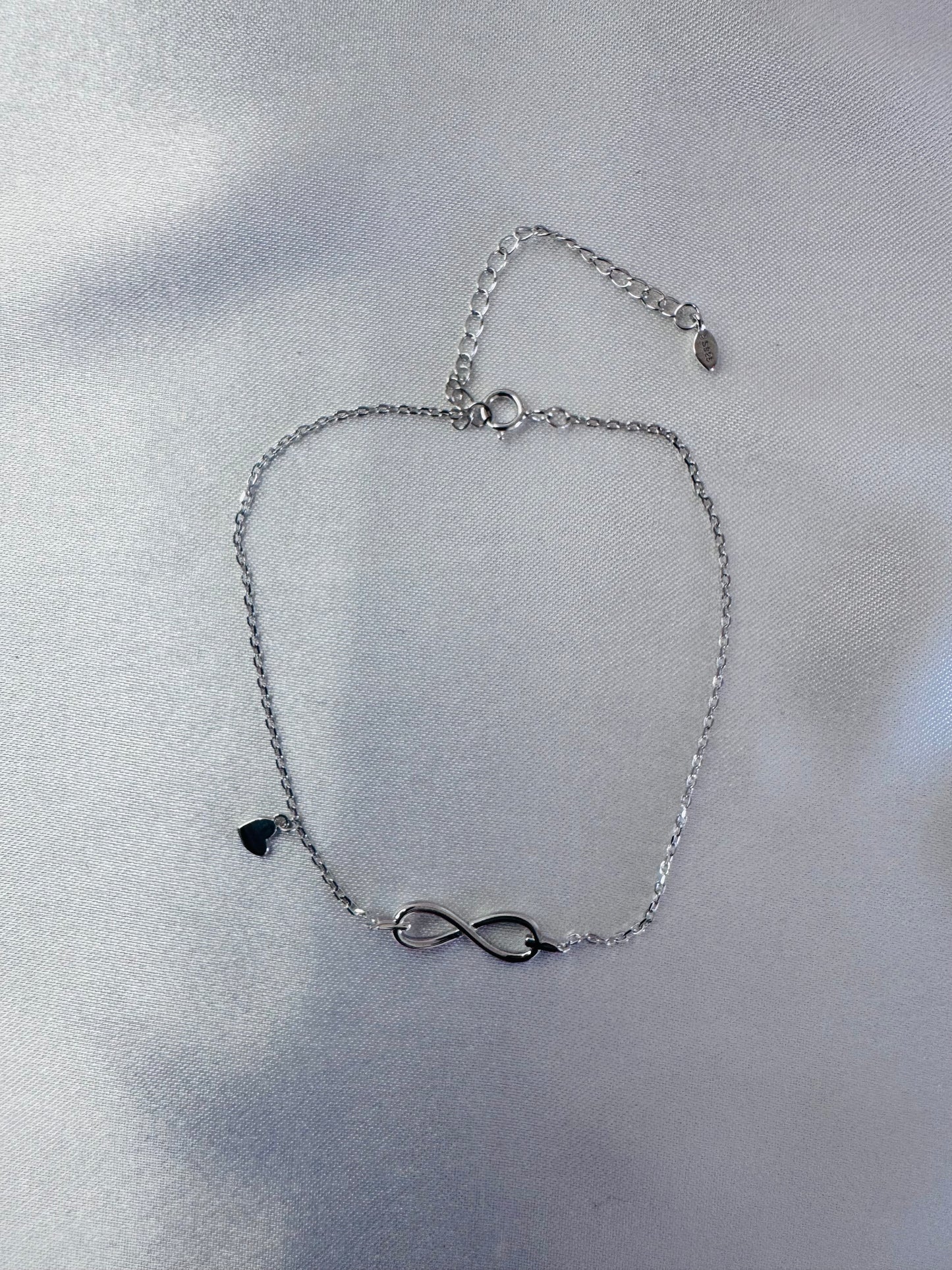 Silver bracelet with an infinity symbol on a light gray background