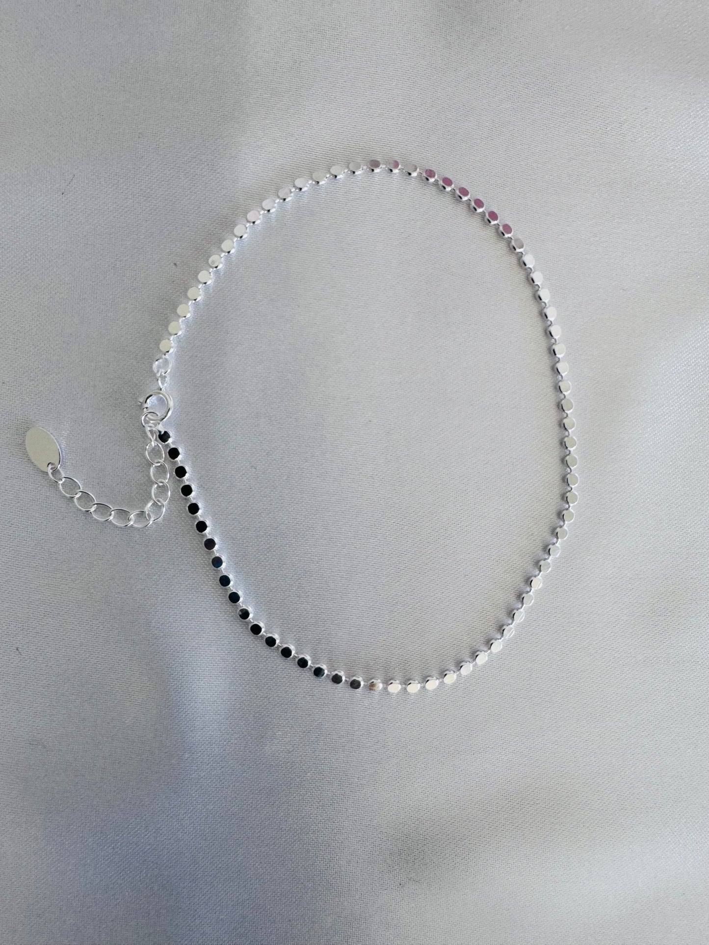 Silver shimmer anklet on a gray background