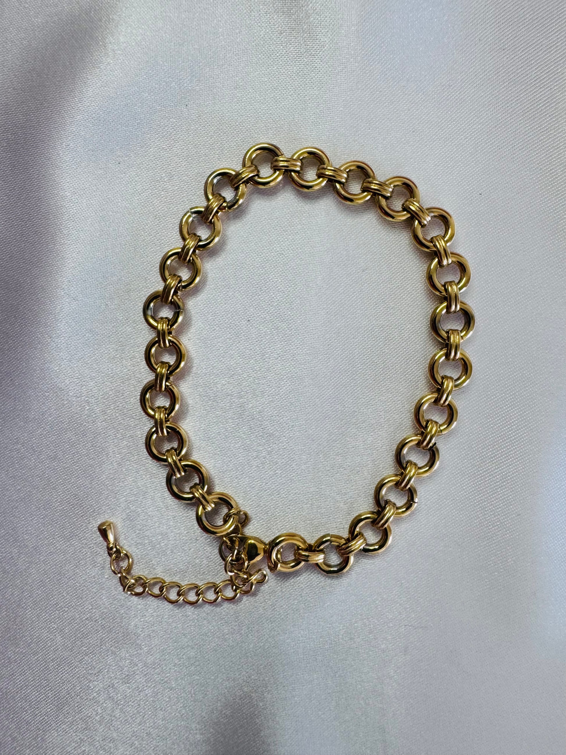Gold chain bracelet on a light gray background