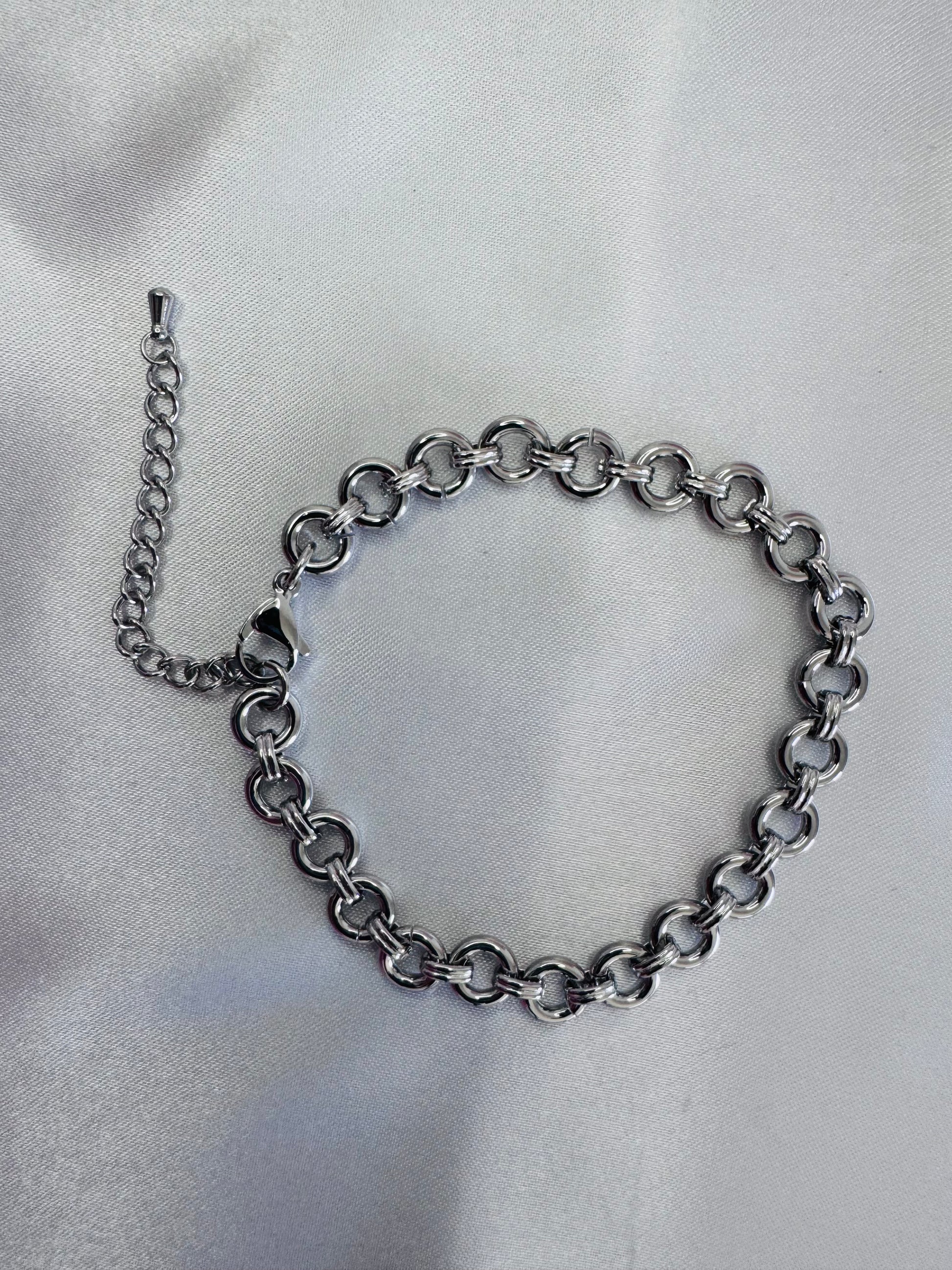 Silver chain bracelet on a light gray fabric background