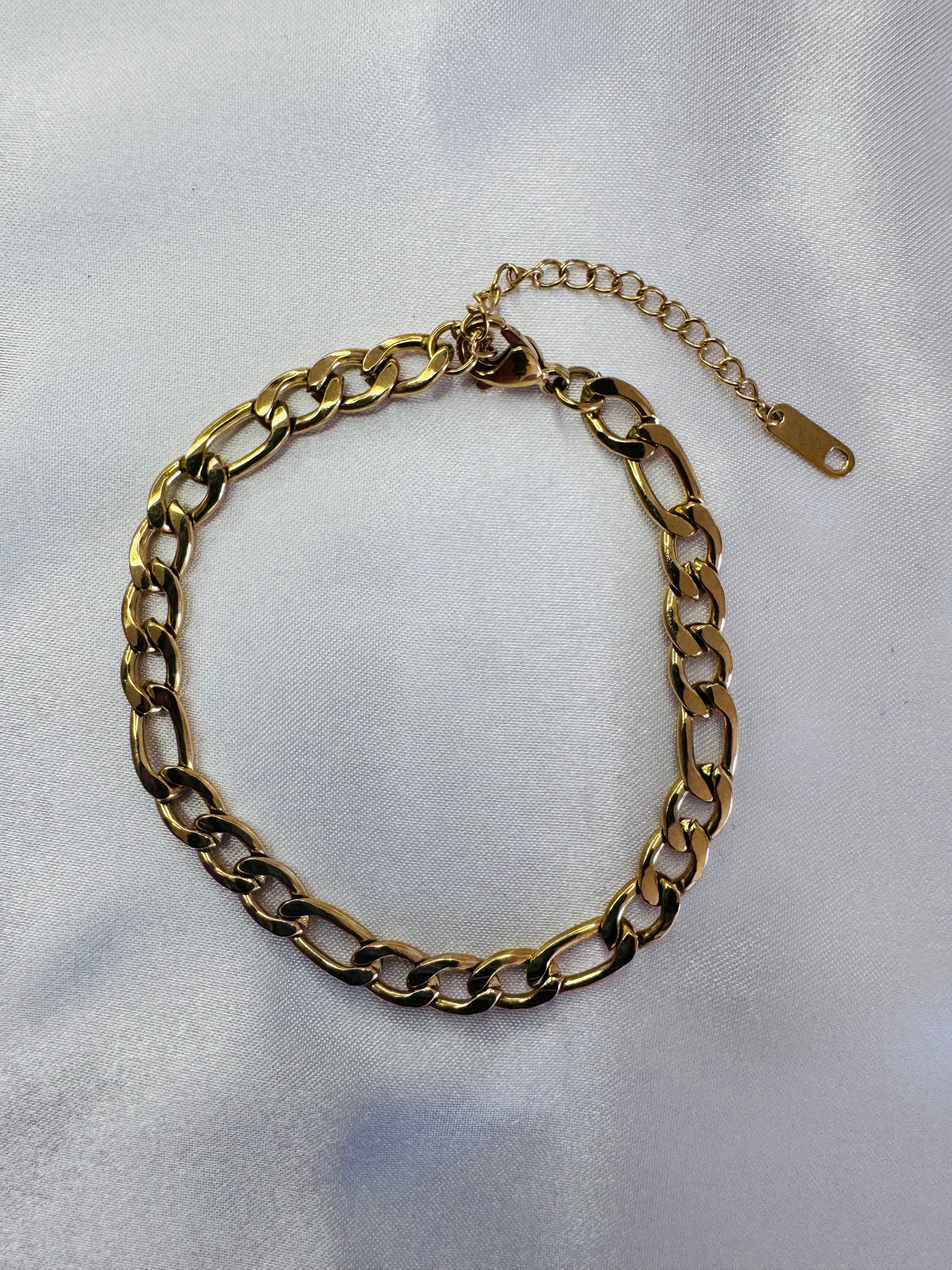 Gold figaro anklet on a light gray background