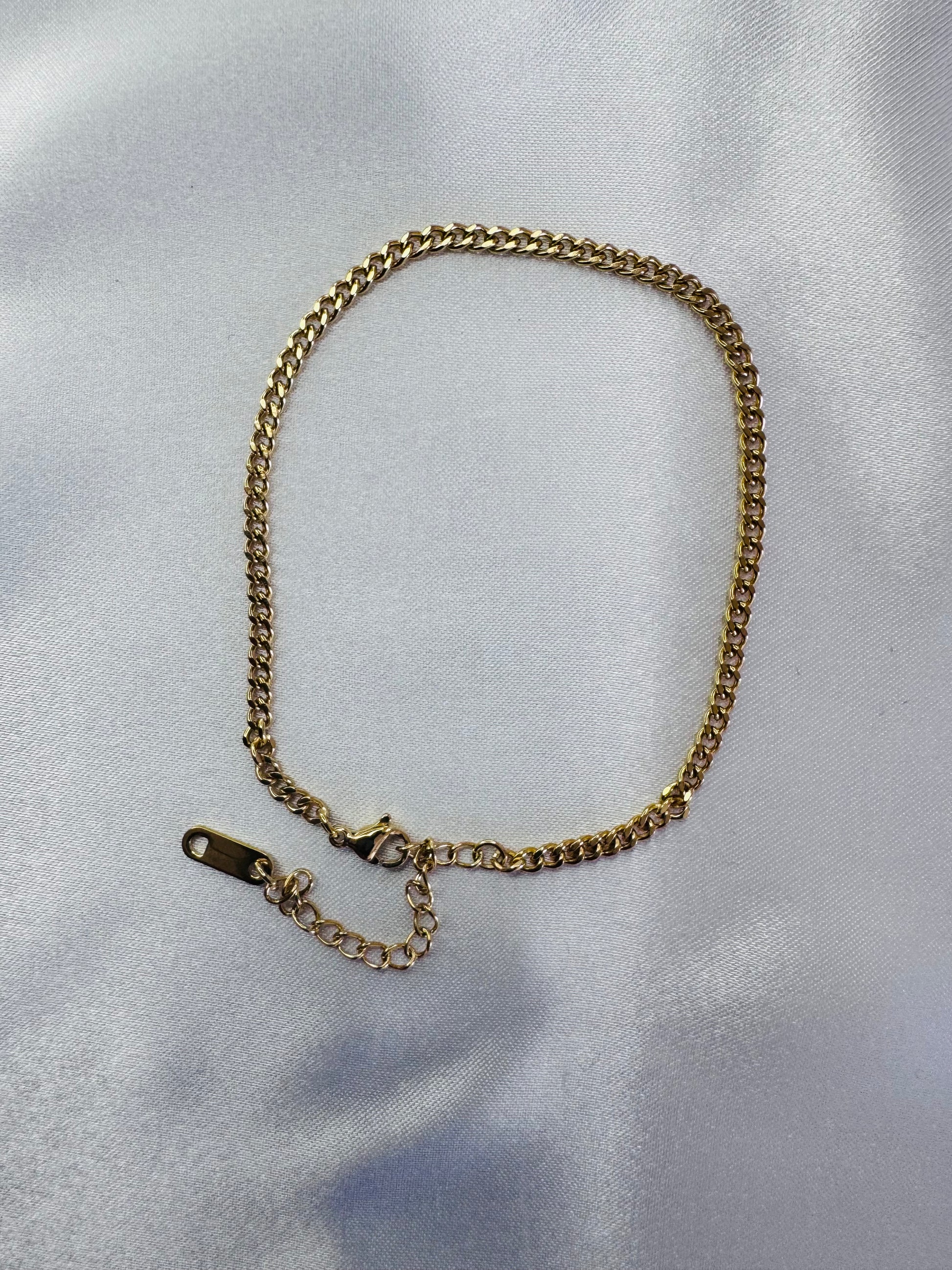 Gold chain anklet on a light gray background