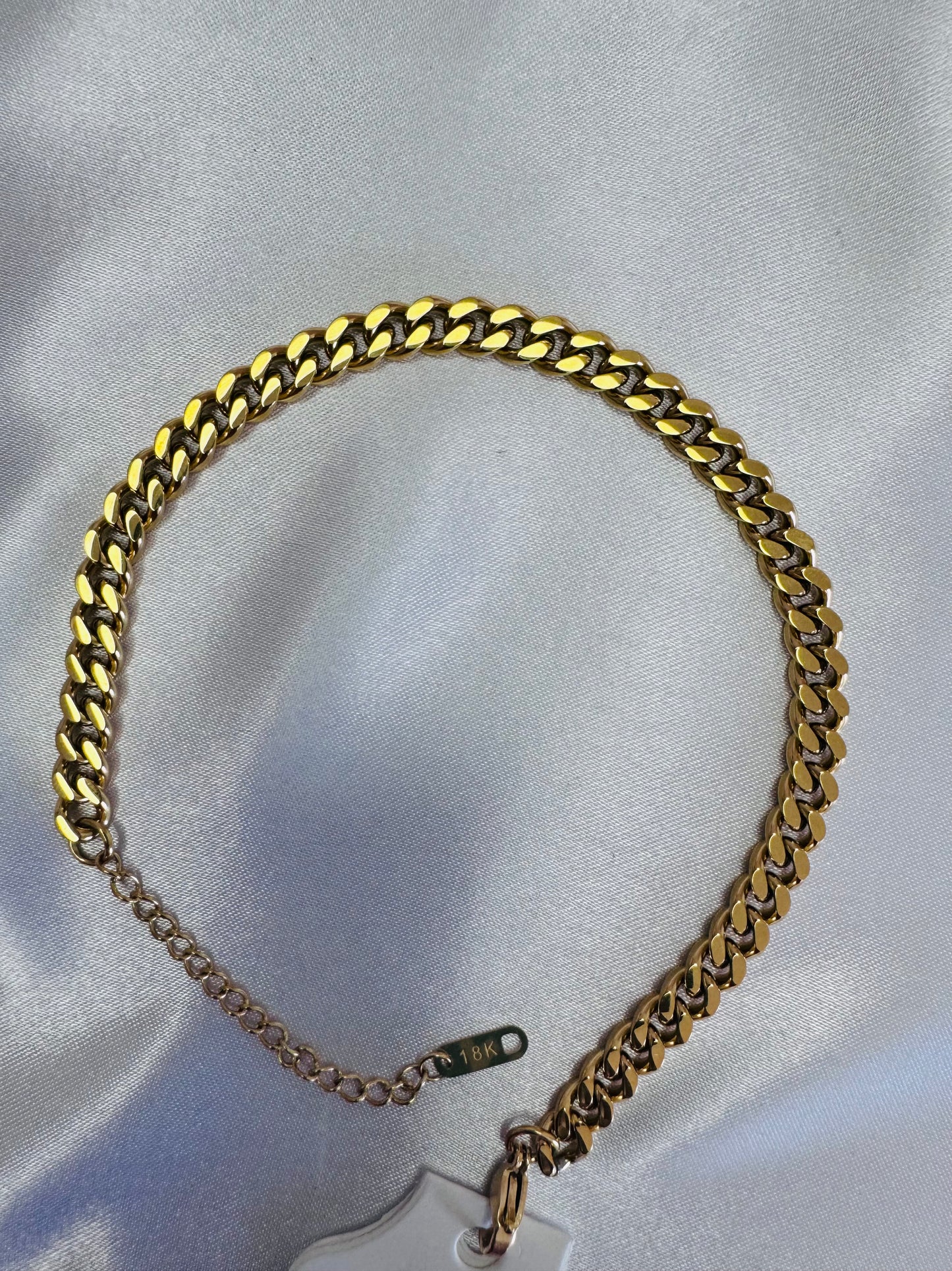 18k cuban link anklet on a light gray background