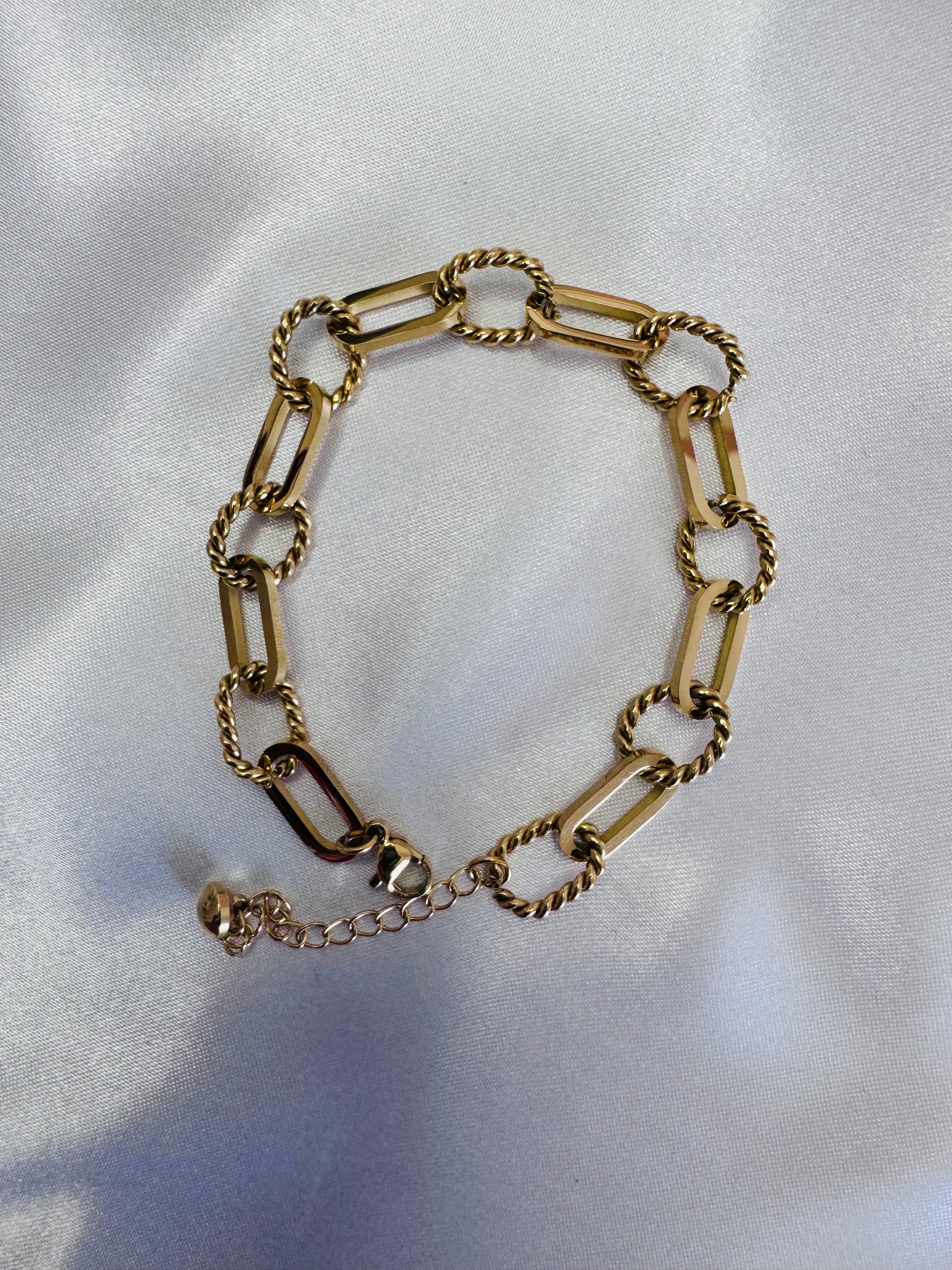 Gold rope anklet on a white fabric background