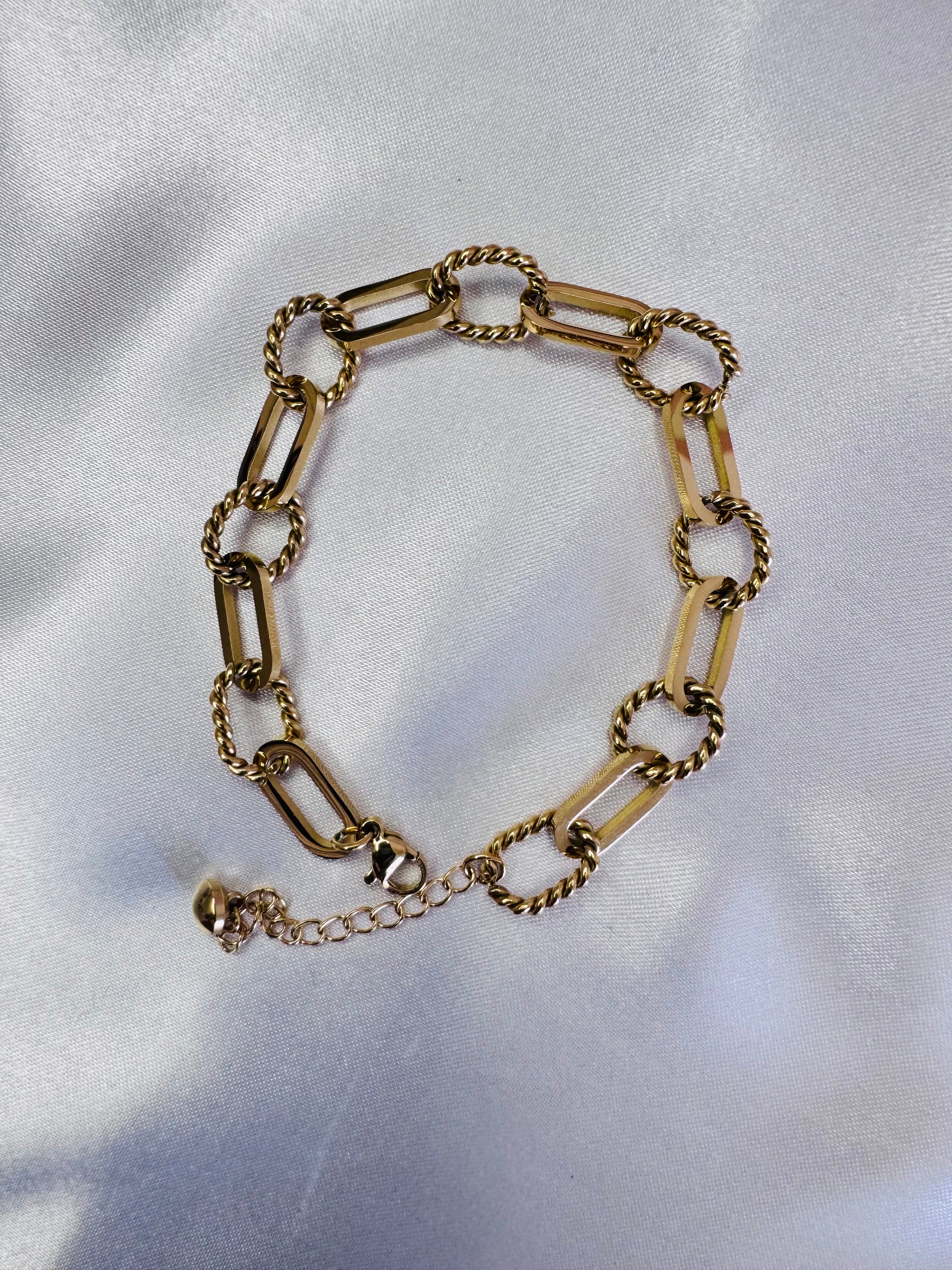 Gold rope anklet on a white fabric background