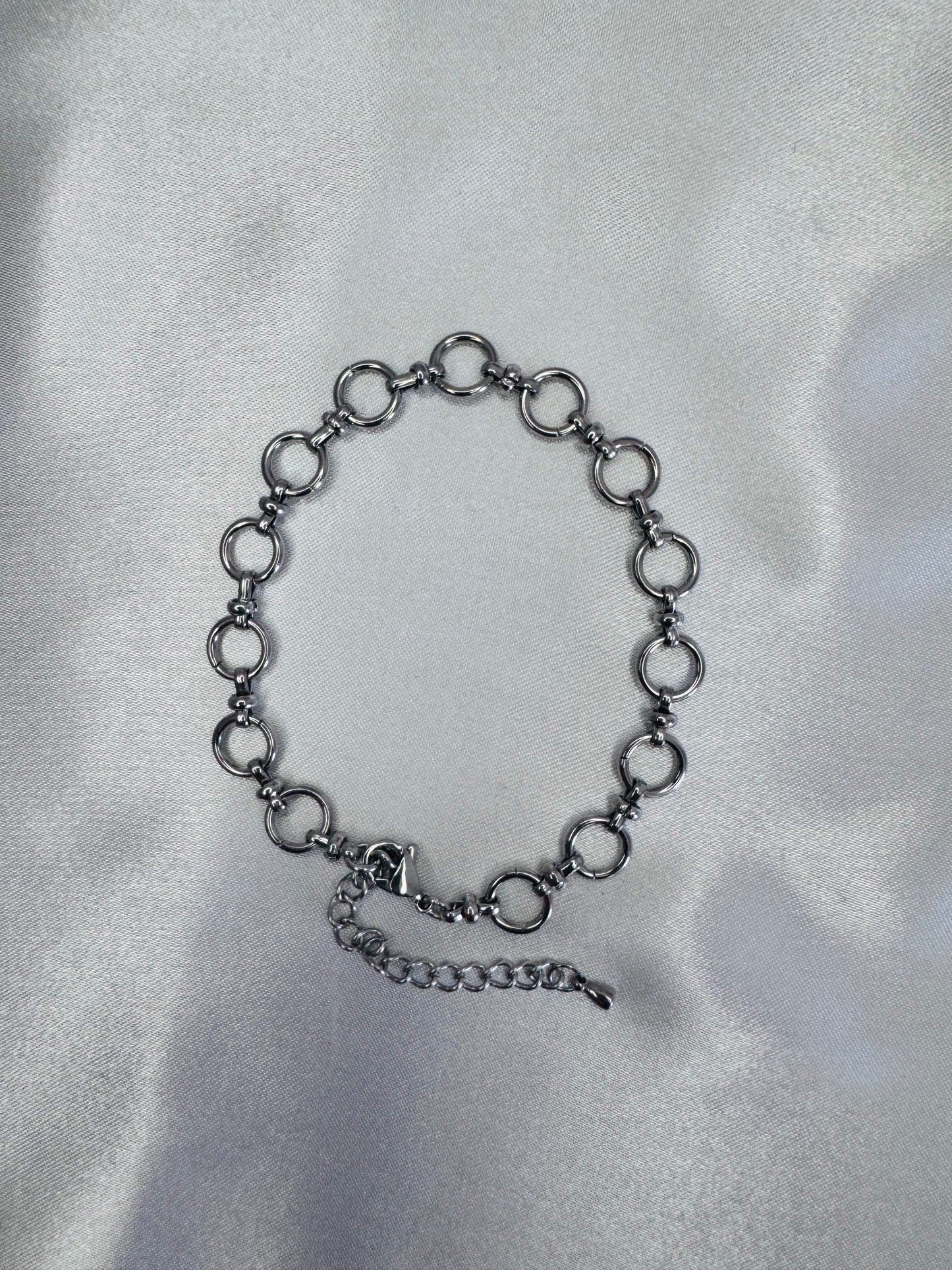 Black chain anklet  on a silver satin background