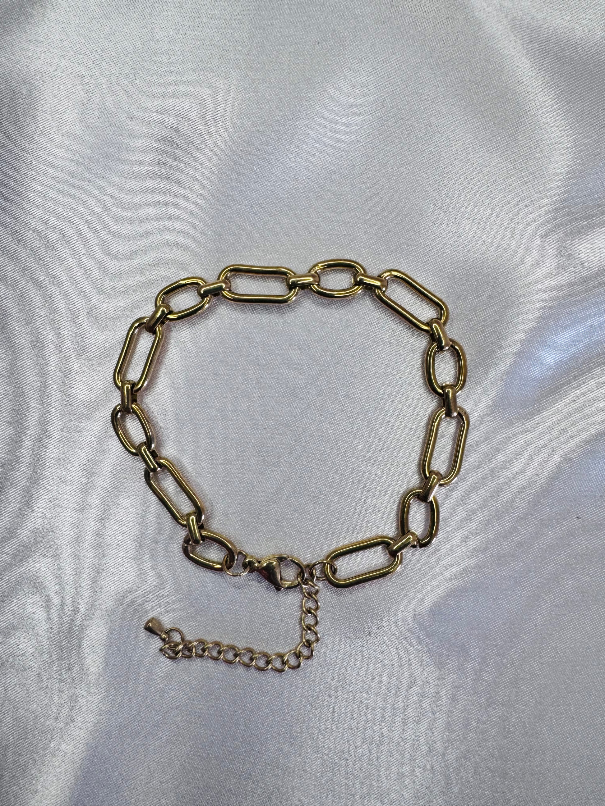 Gold chain anklet on a silver satin background