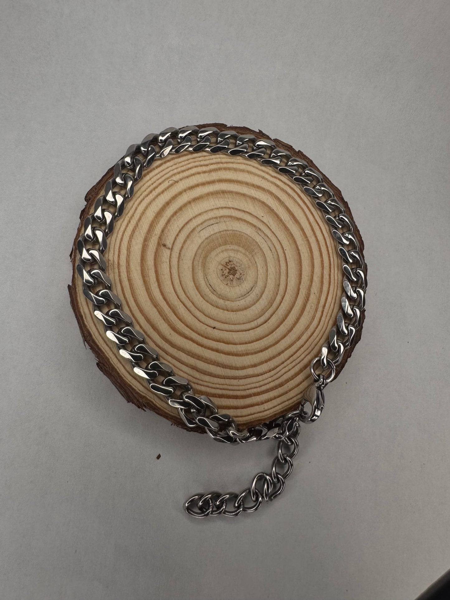 Wooden disc with silver anklet chain on a gray background