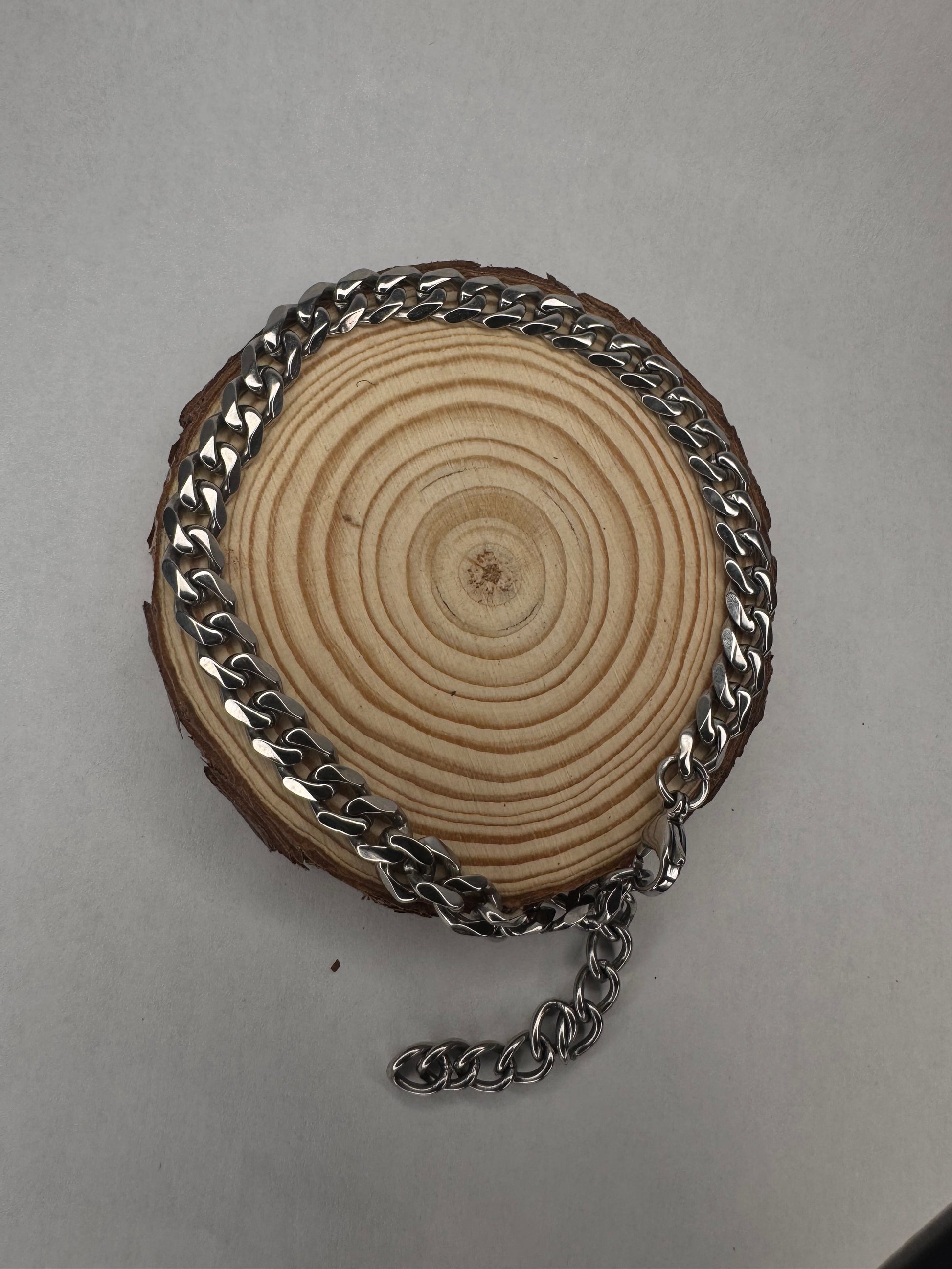 Wooden disc with silver anklet chain on a gray background