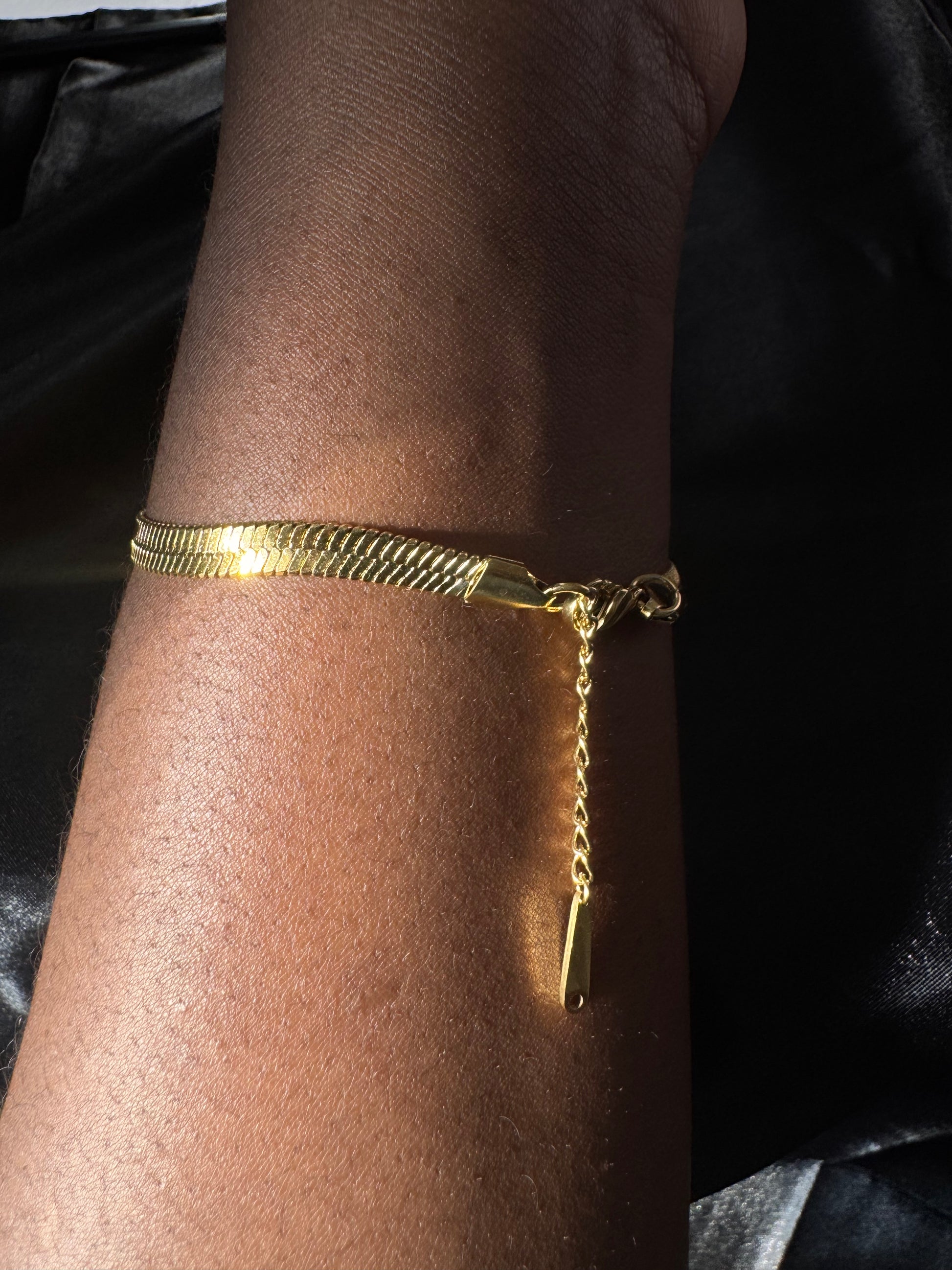 Gold bracelet on a wrist with a dark background