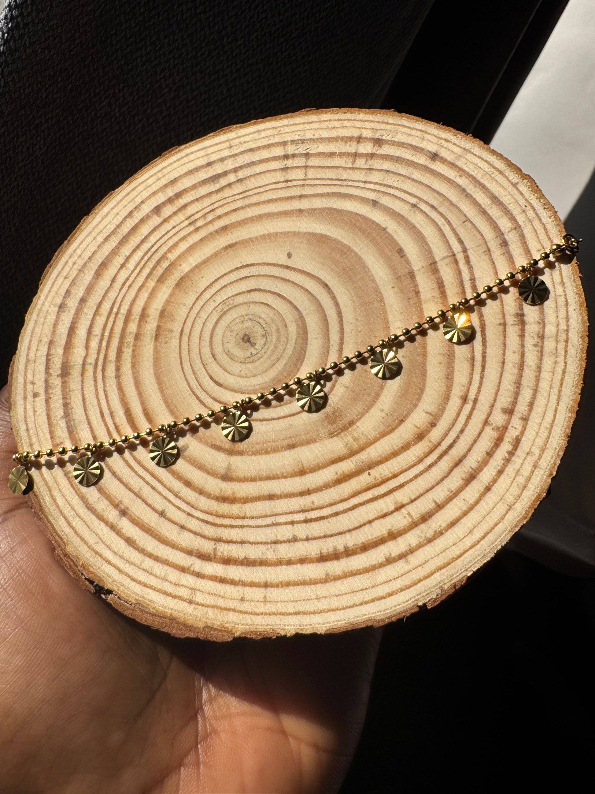 Gold chain anklet on a wooden surface