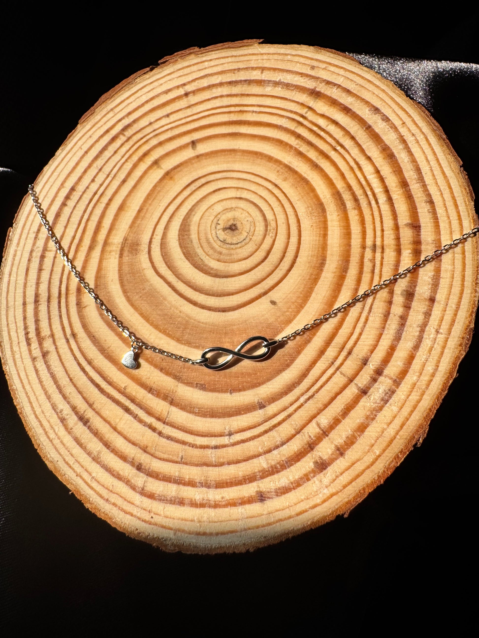 Necklace with an infinity symbol pendant on a wooden log