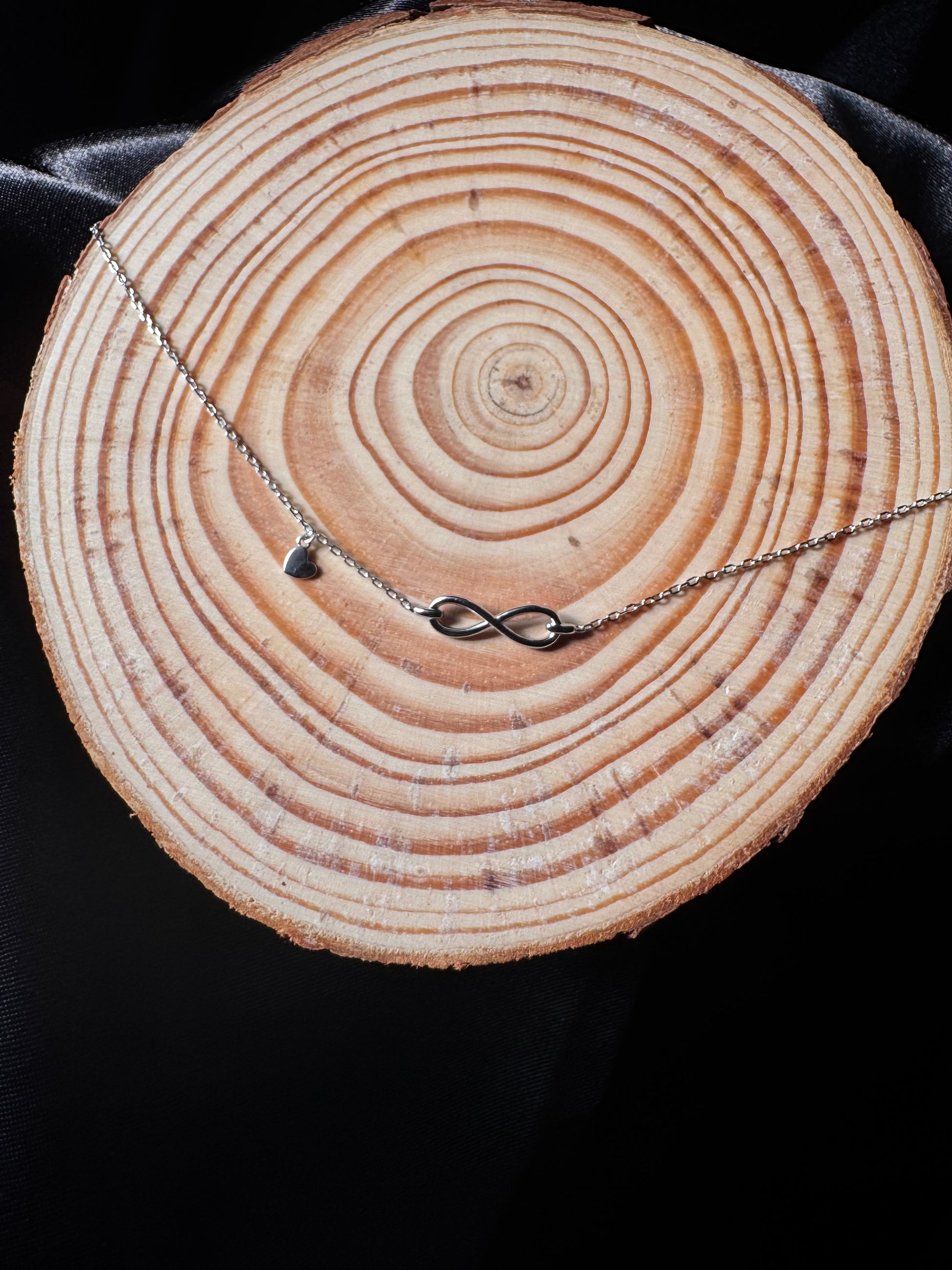 anklet with a heart pendant on a wooden log