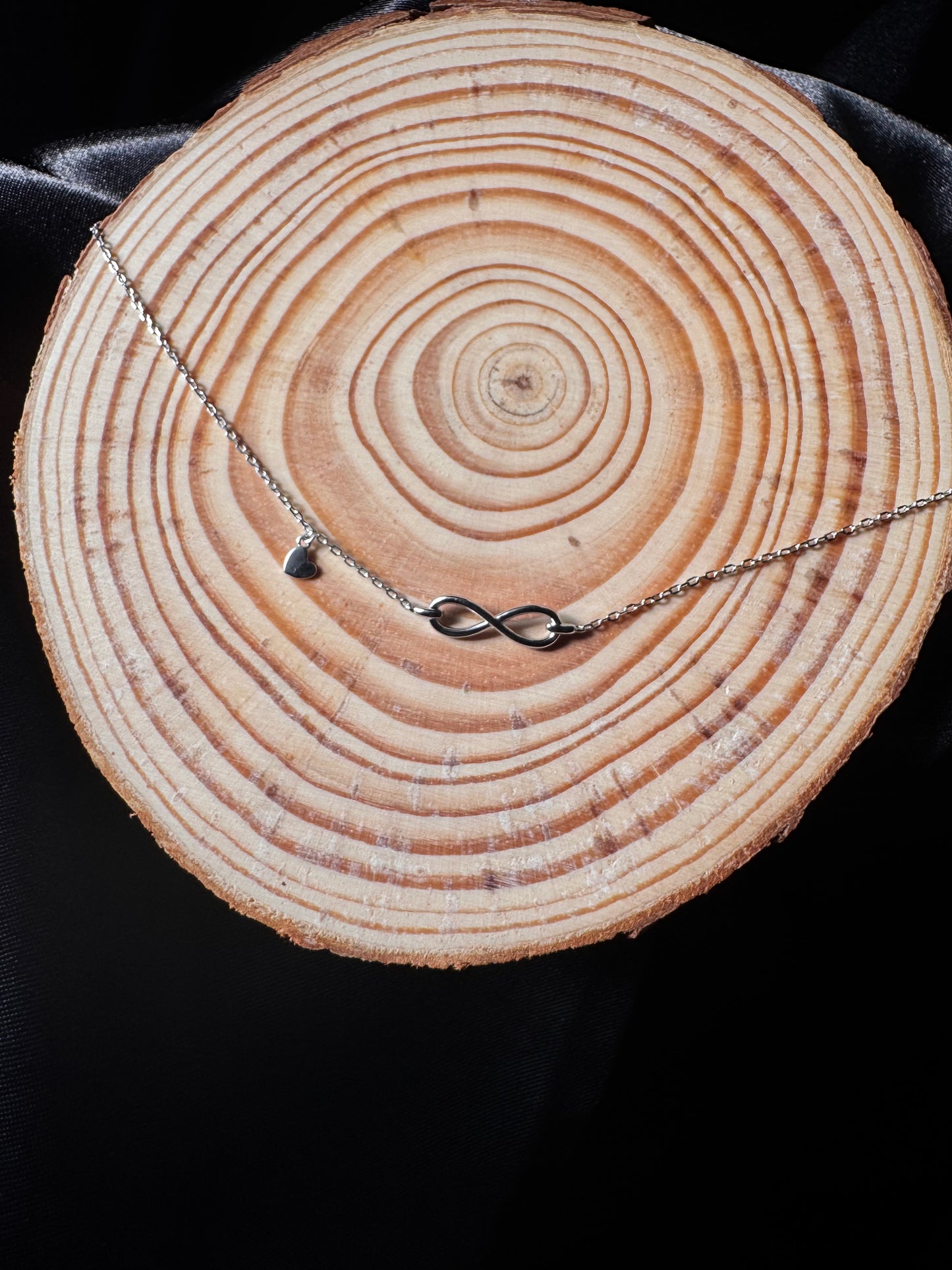 Anklet with a heart pendant on a wooden log