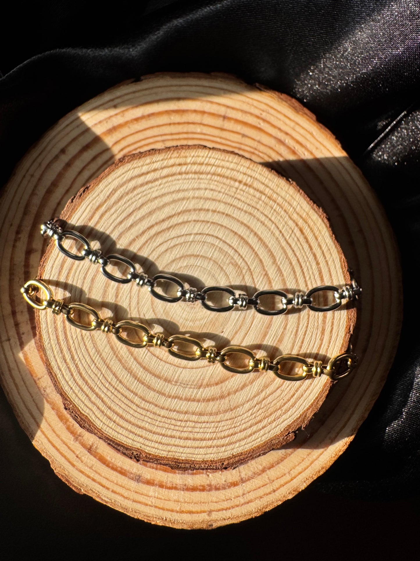 Two gold and silver anklets on a wooden surface