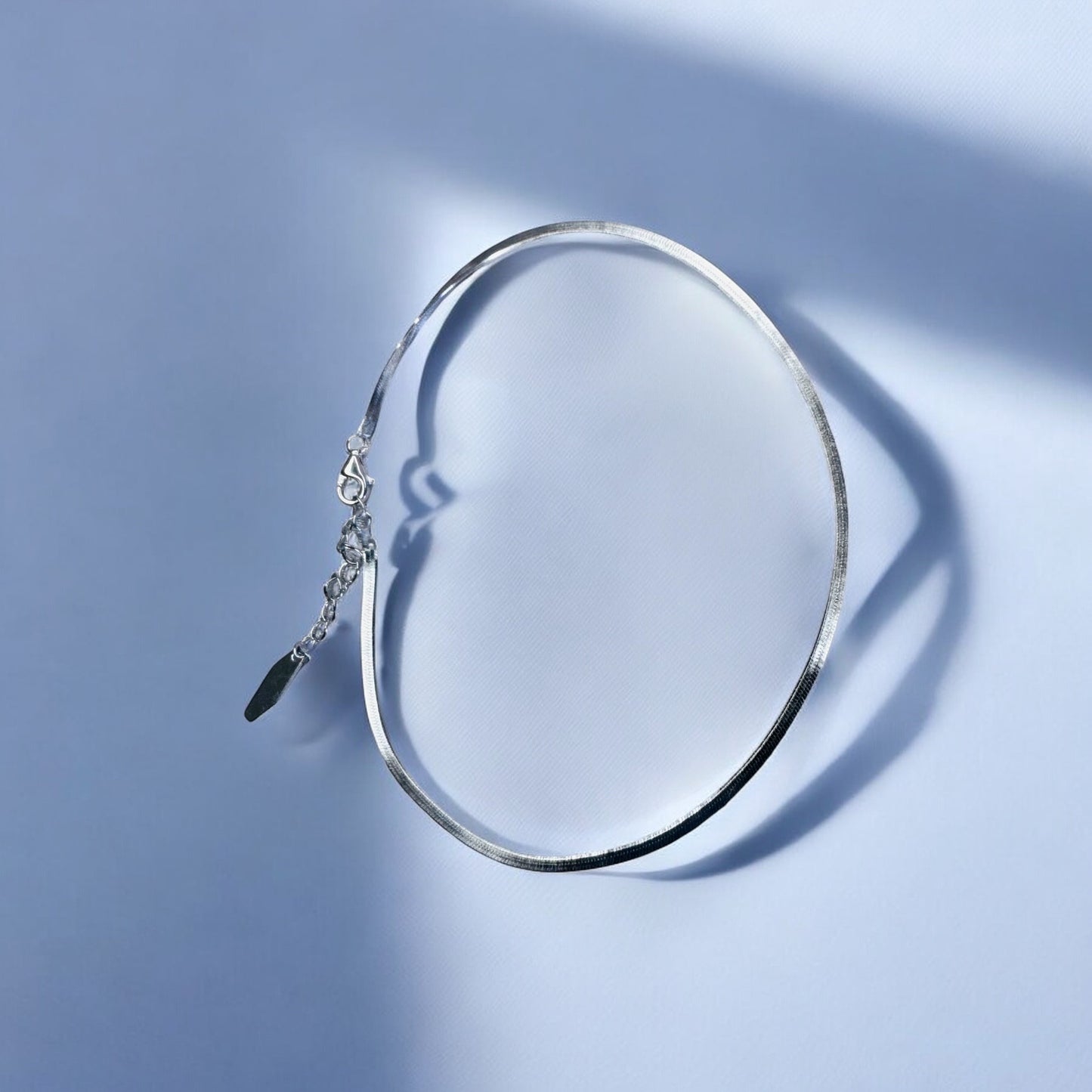 Silver anklet on a light blue background