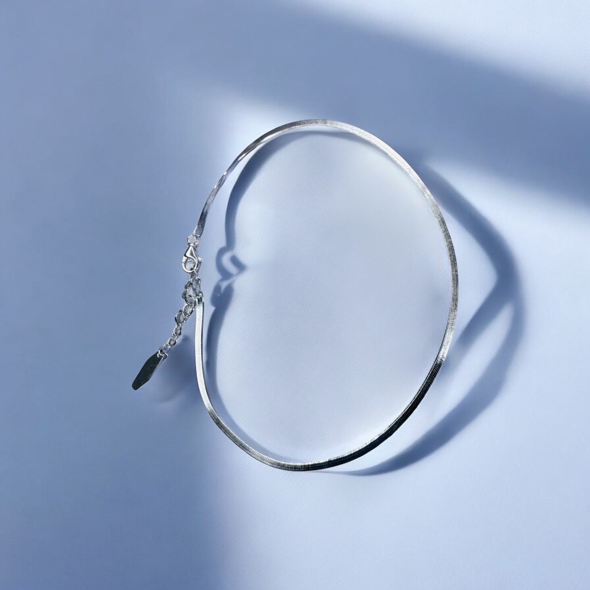 Silver anklet on a light blue background