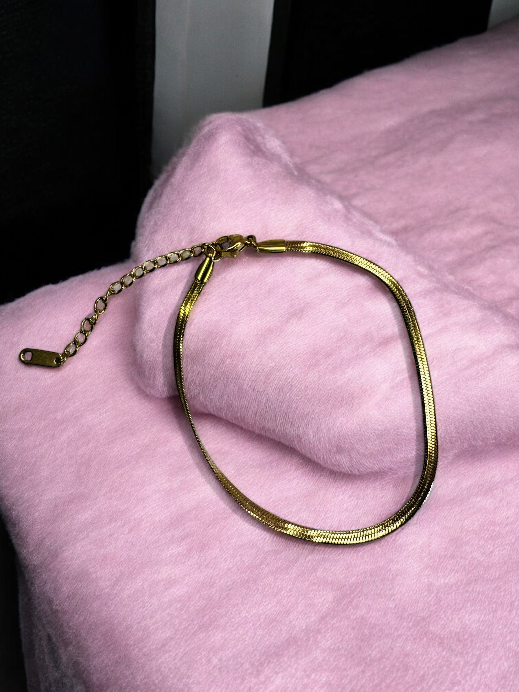 Gold necklace on a pink surface