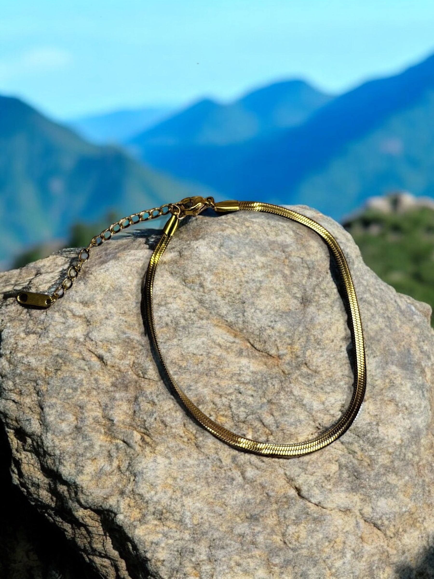 Gold necklace on a rock with a mountainous background