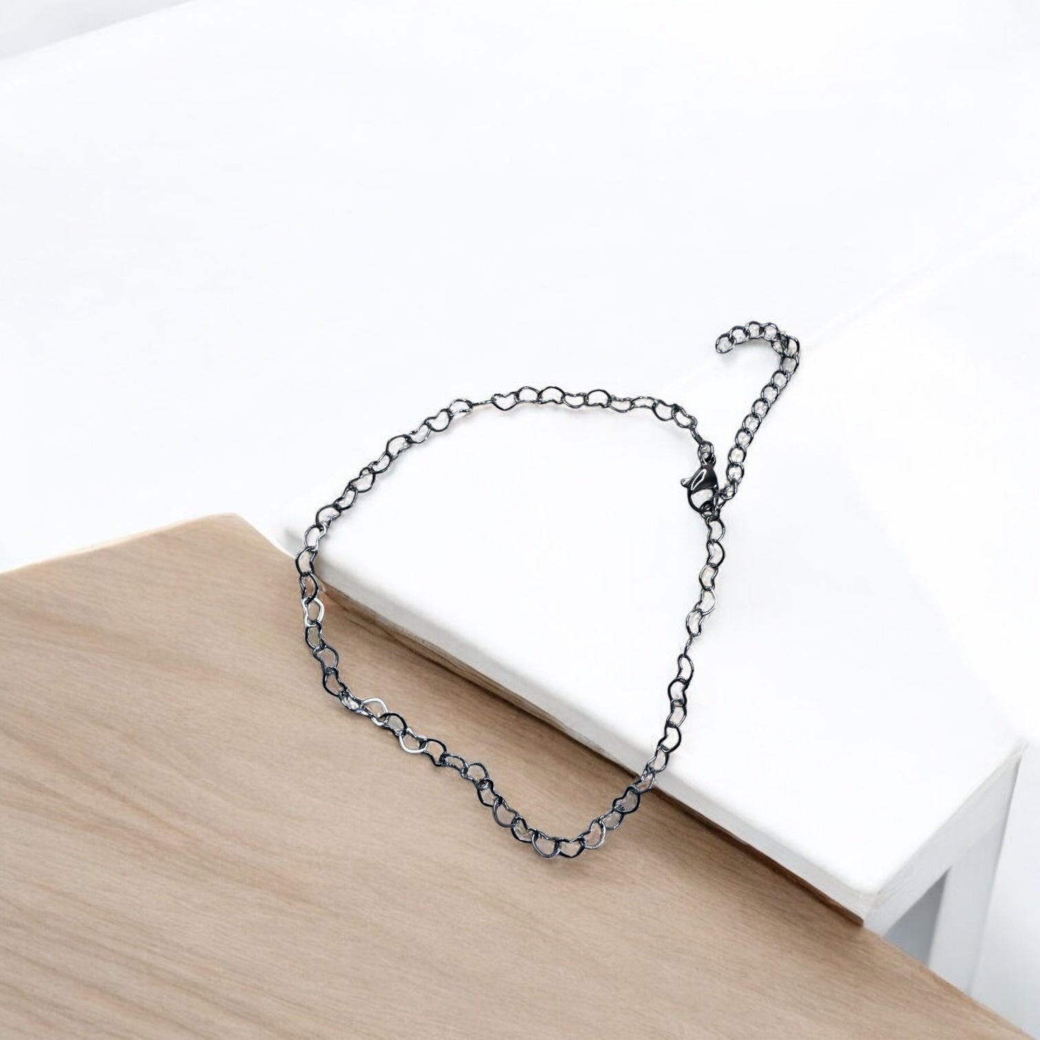 Silver chain bracelet on a wooden surface with a white background