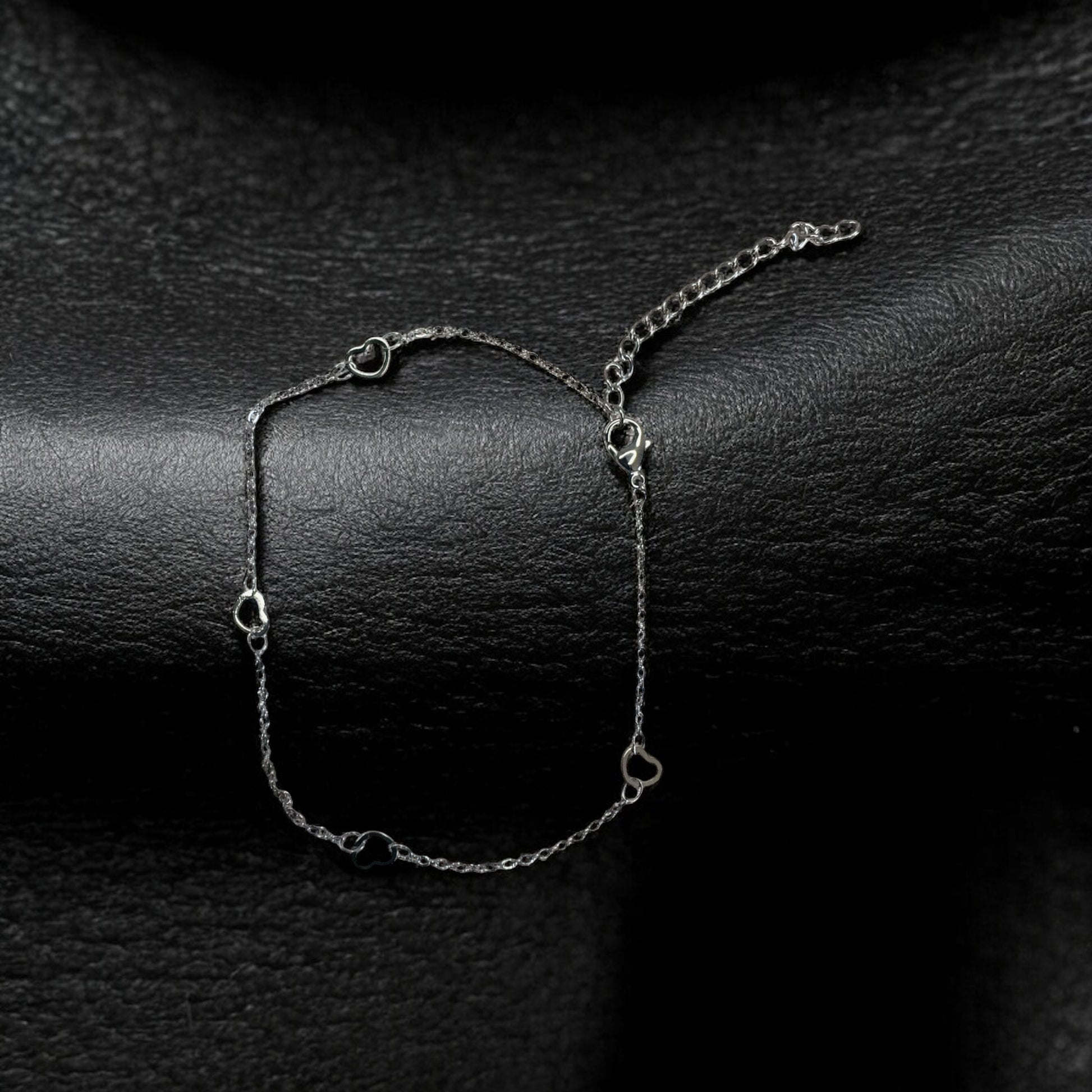 Silver anklet on a dark textured surface