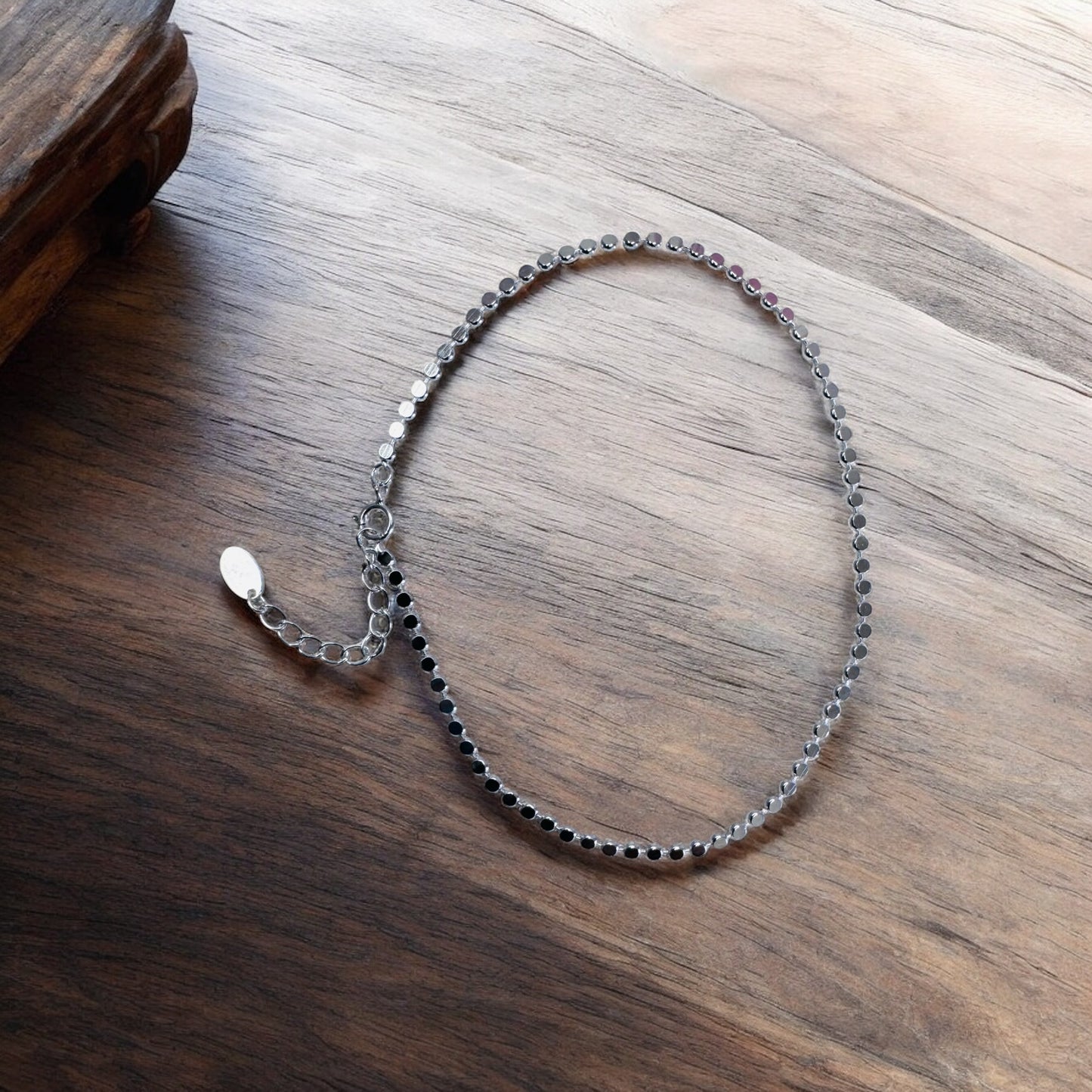 Silver shimmer anklet on a wooden surface