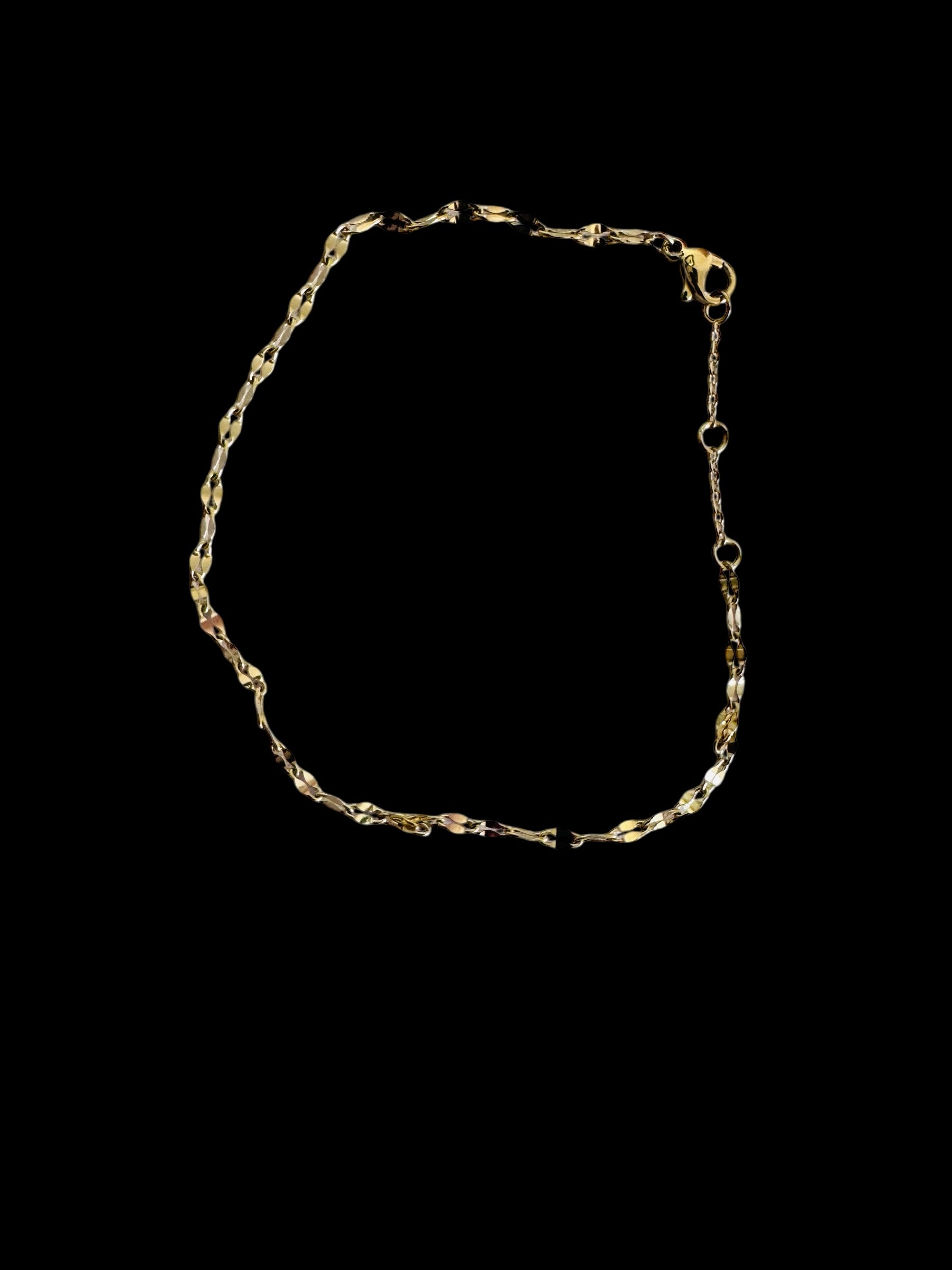 Gold twinkle anklet on a black background