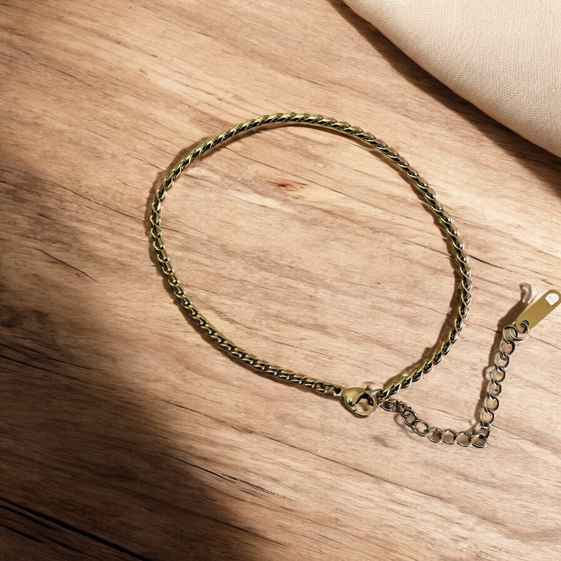 Gold twist rope anklet on a wooden surface
