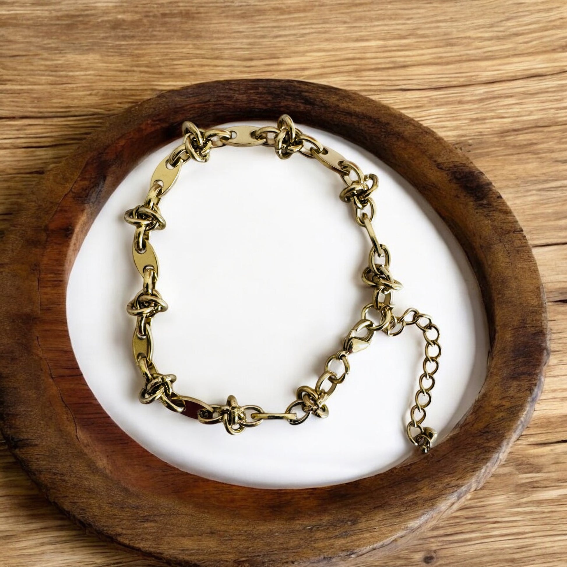 Gold anklet on a white stone surface inside a wooden bowl