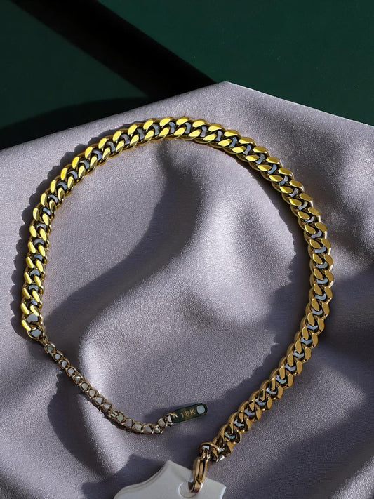 18k. cuban link anklet with a cross pendant on a gray surface