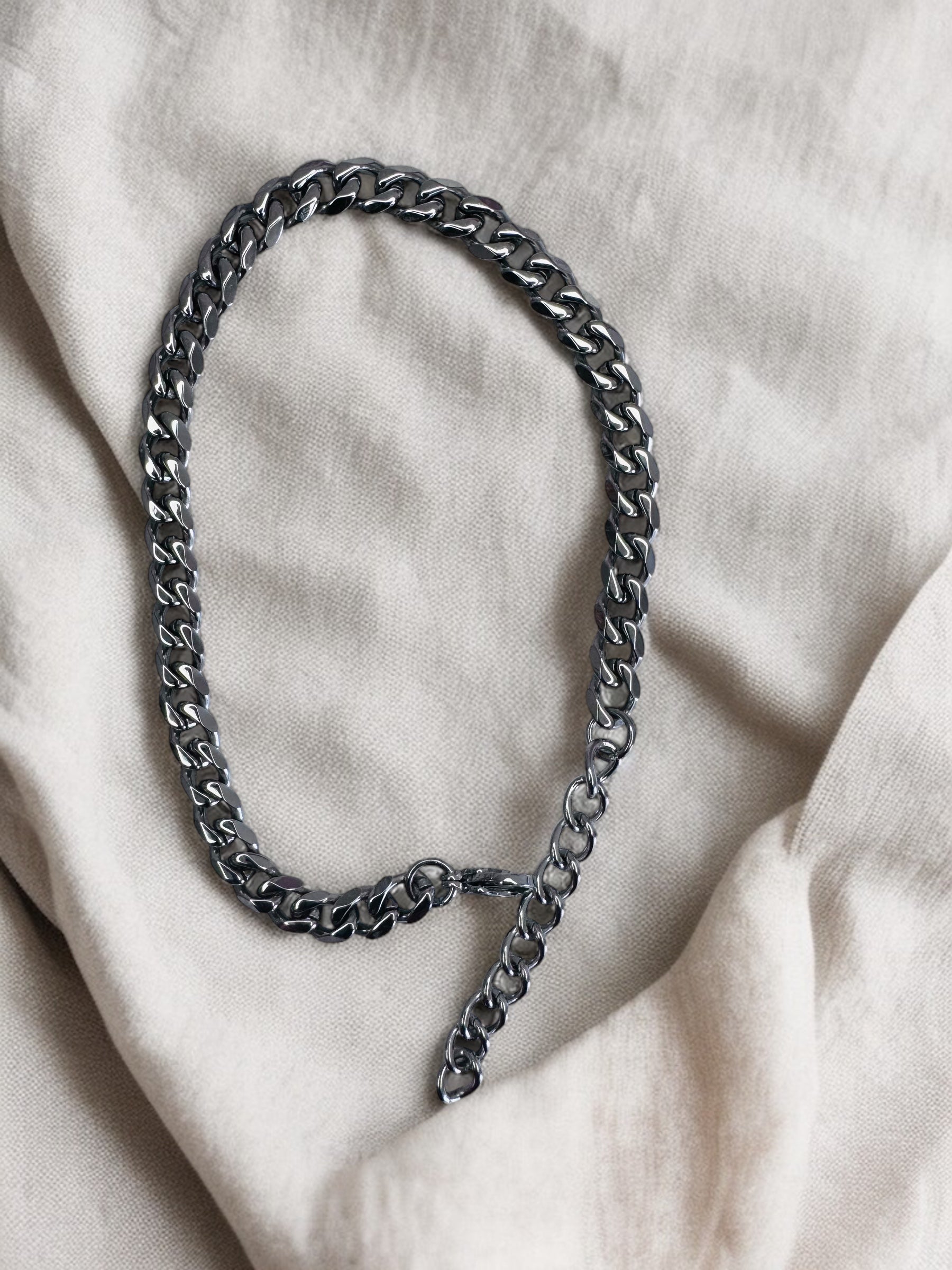 Silver anklet on a light fabric background