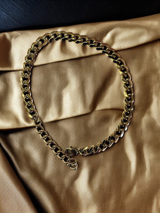 Gold chain anklet on a beige-gold fabric background