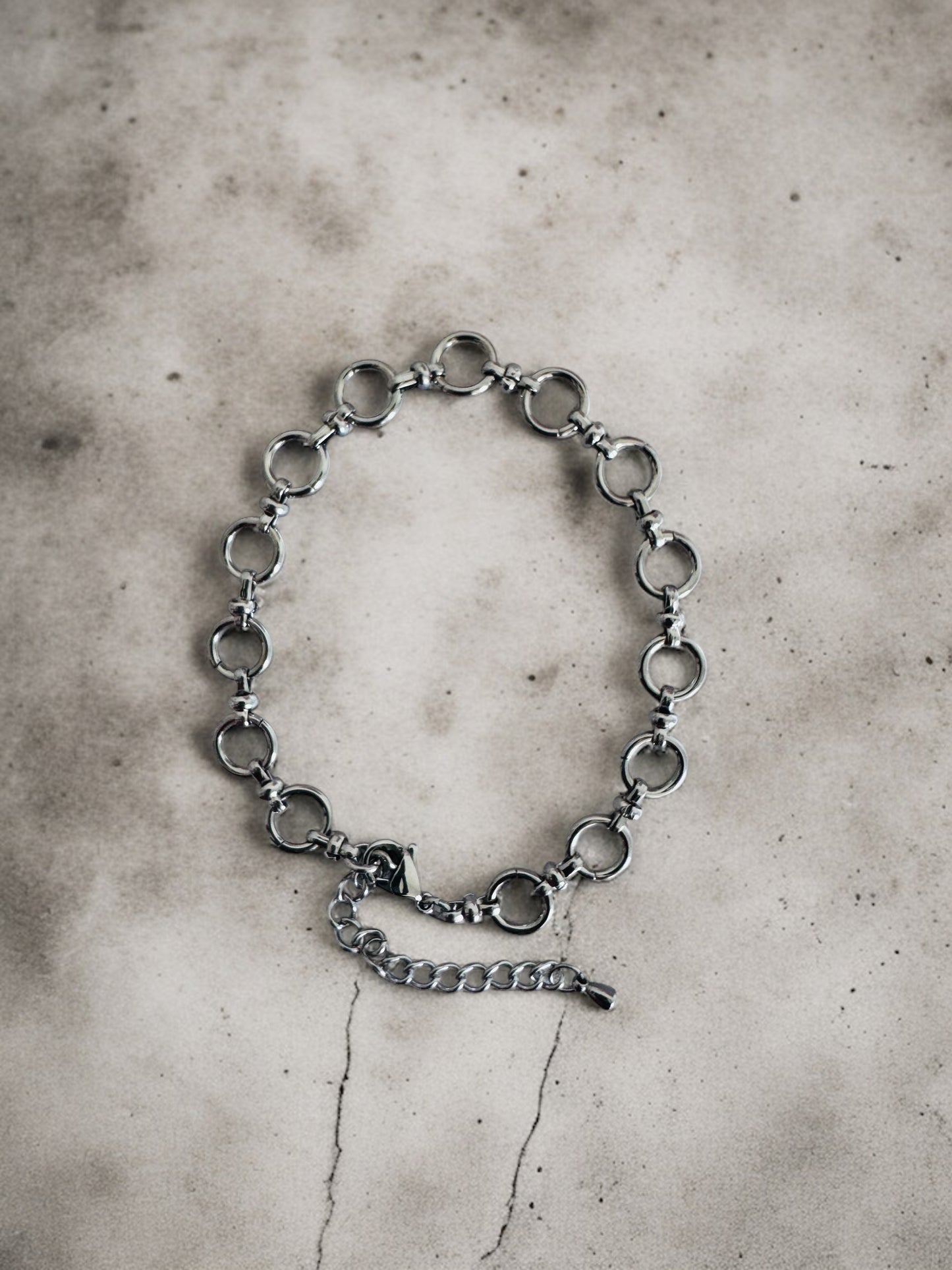 Silver chain anklet on a textured gray surface