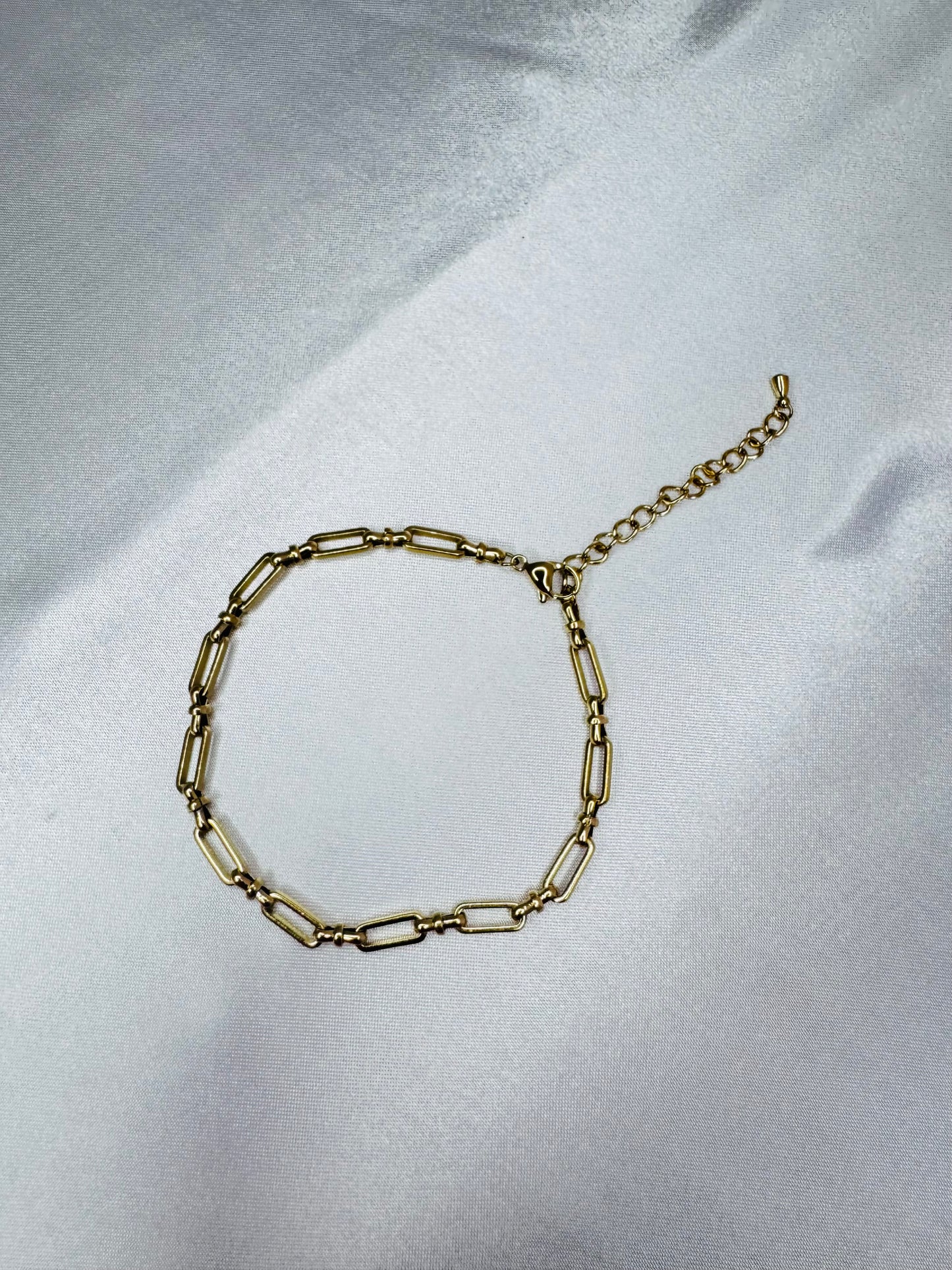 Gold bold link anklet on a light gray fabric background