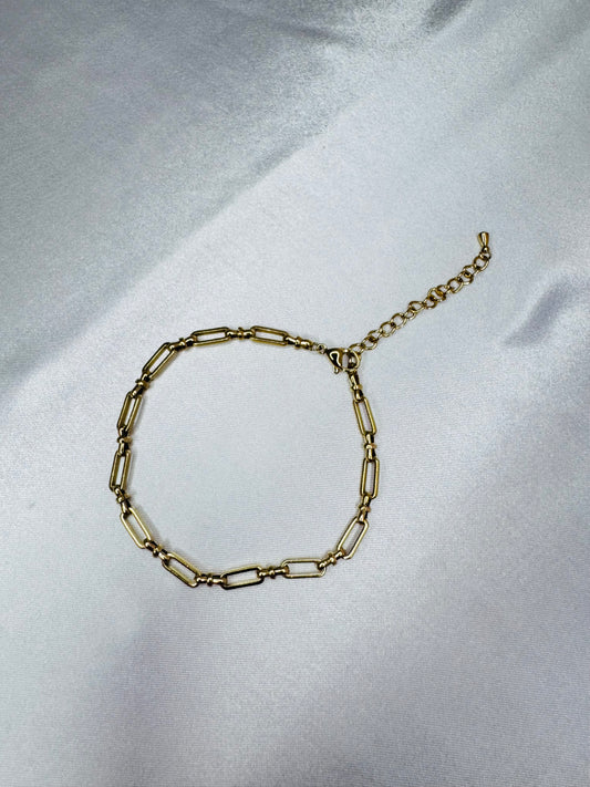 Gold bold link anklet on a light gray fabric background