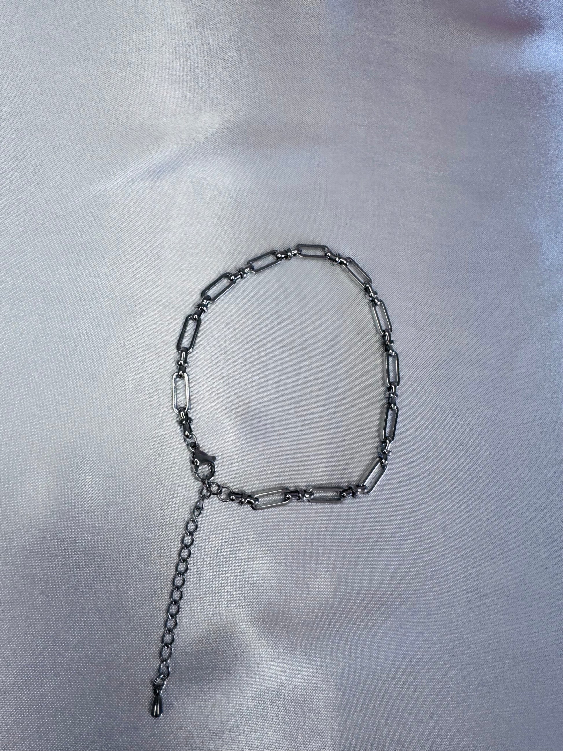 Silver bold link anklet on a reflective silver surface