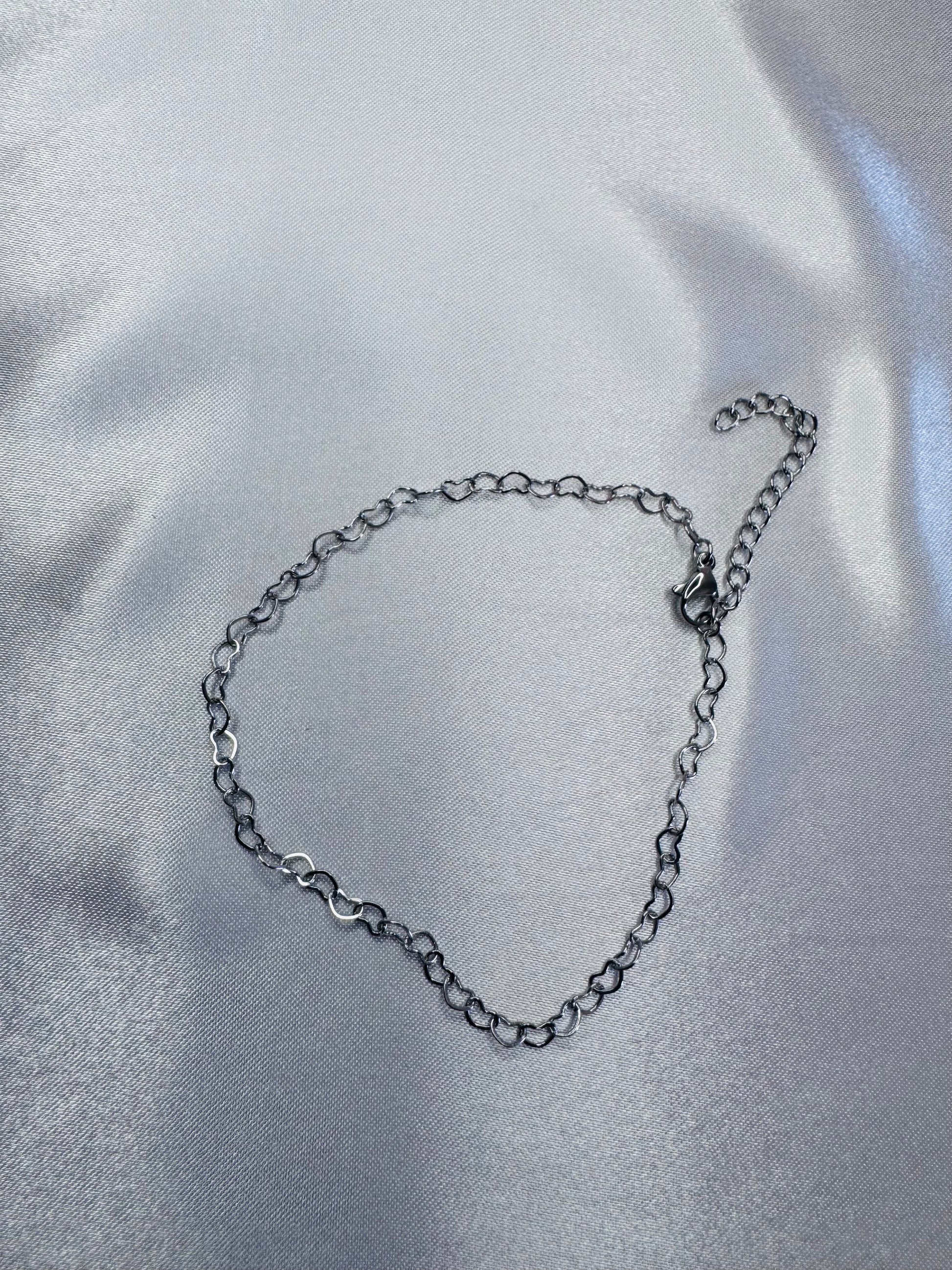 Silver chain bracelet on a reflective silver surface