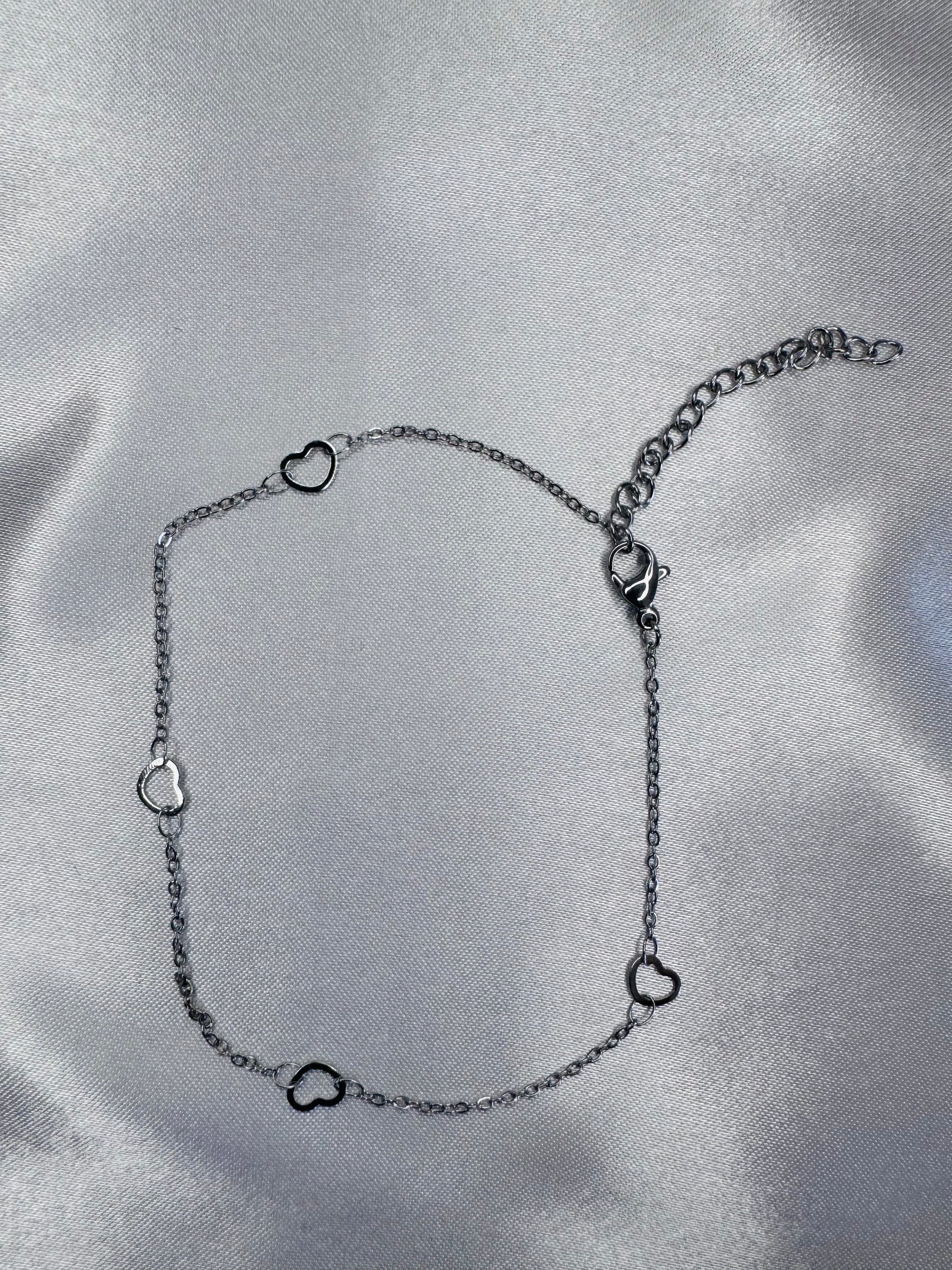 Silver anklet with heart-shaped links on a satin surface
