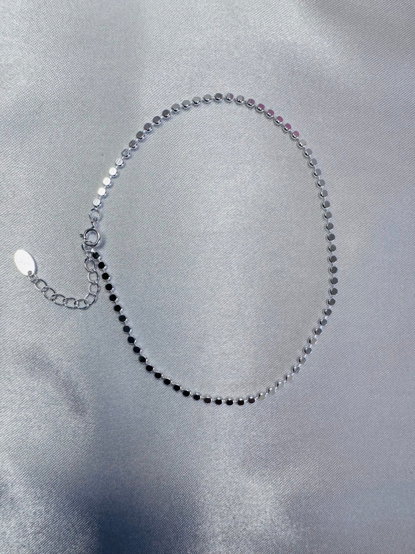 Silver shimmer anklet on a gray satin background