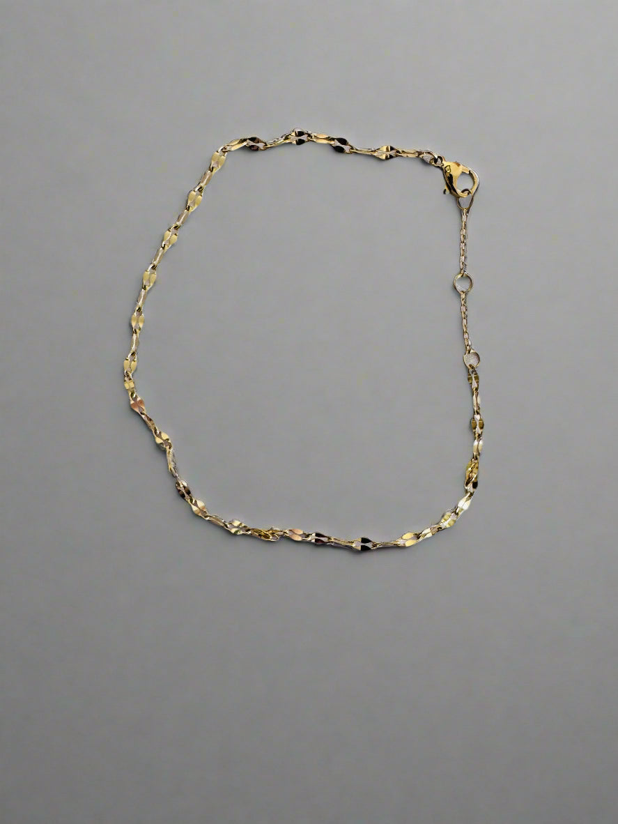 Gold twinkle anklet on a light gray background