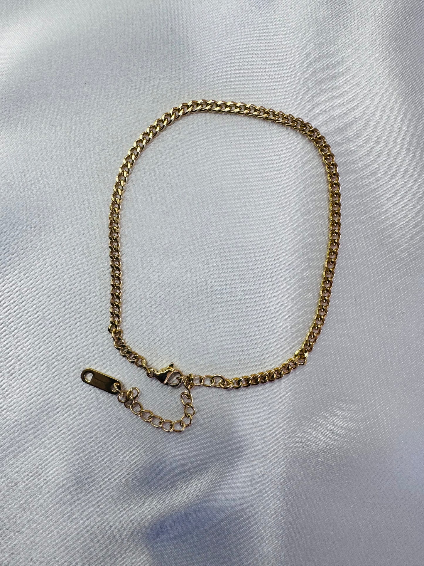 Gold chain anklet on a light gray background
