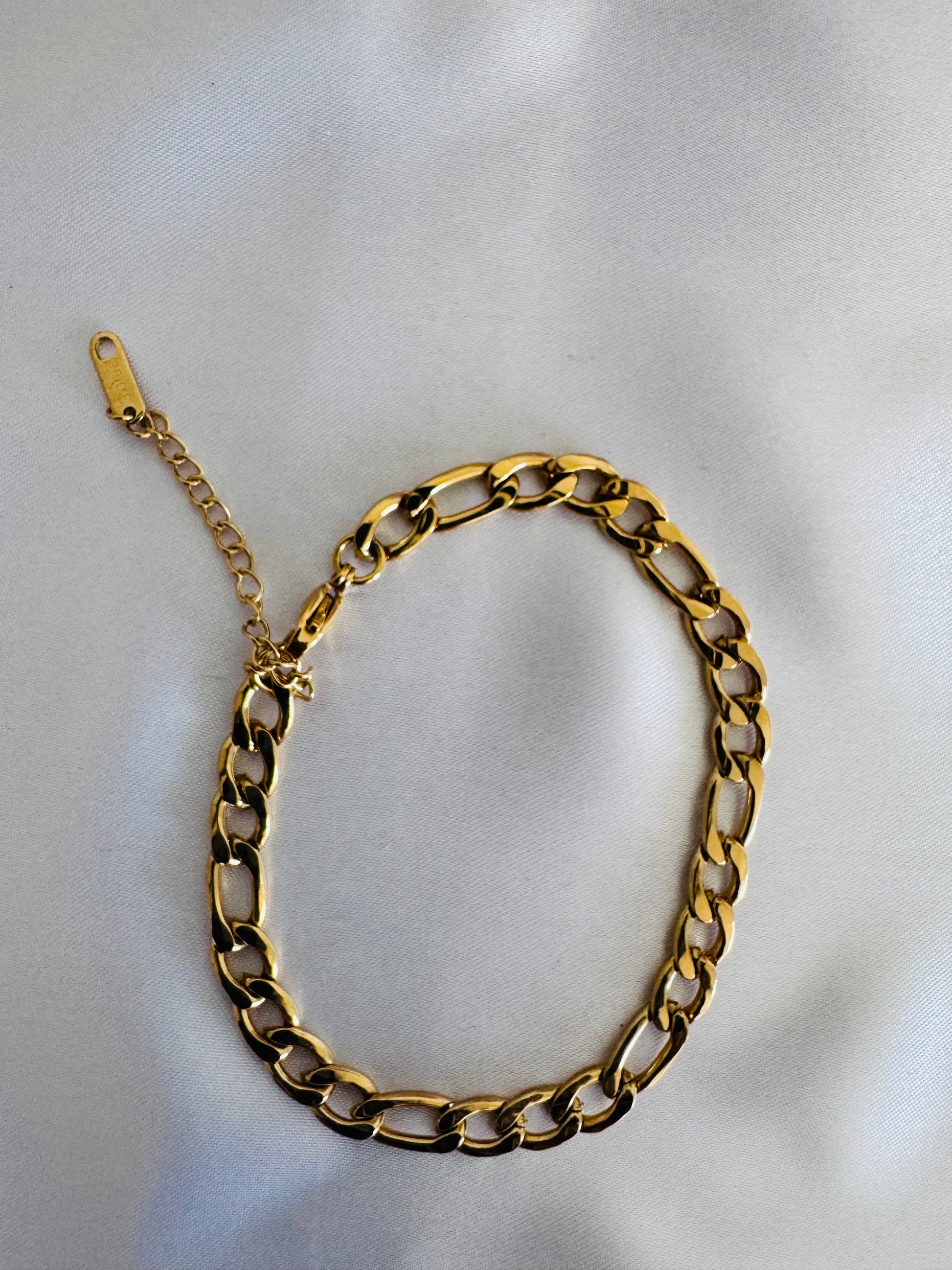 Gold figaro anklet on  a light gray background